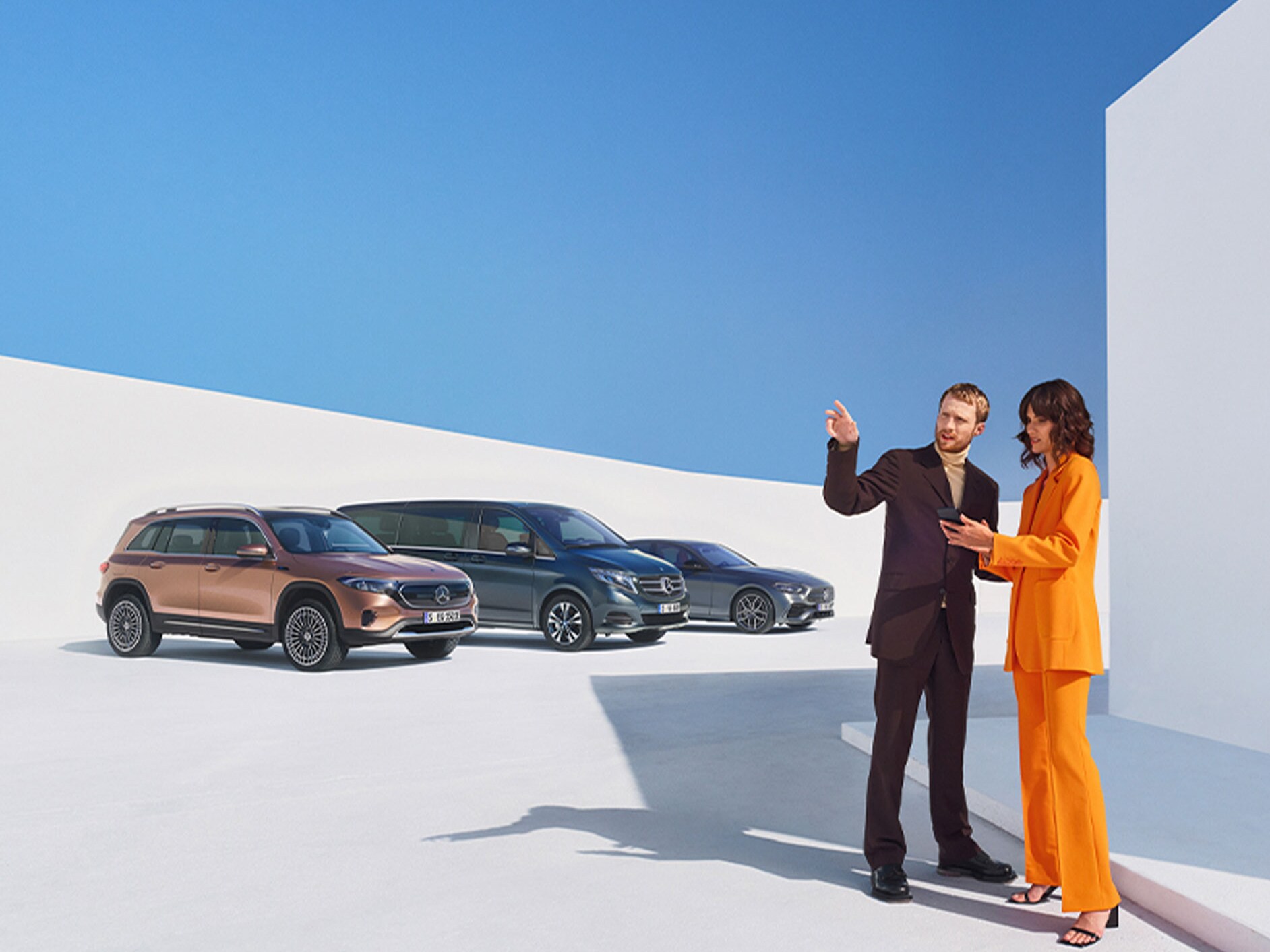 Un homme et une femme devant plusieurs véhicules Mercedes-Benz.