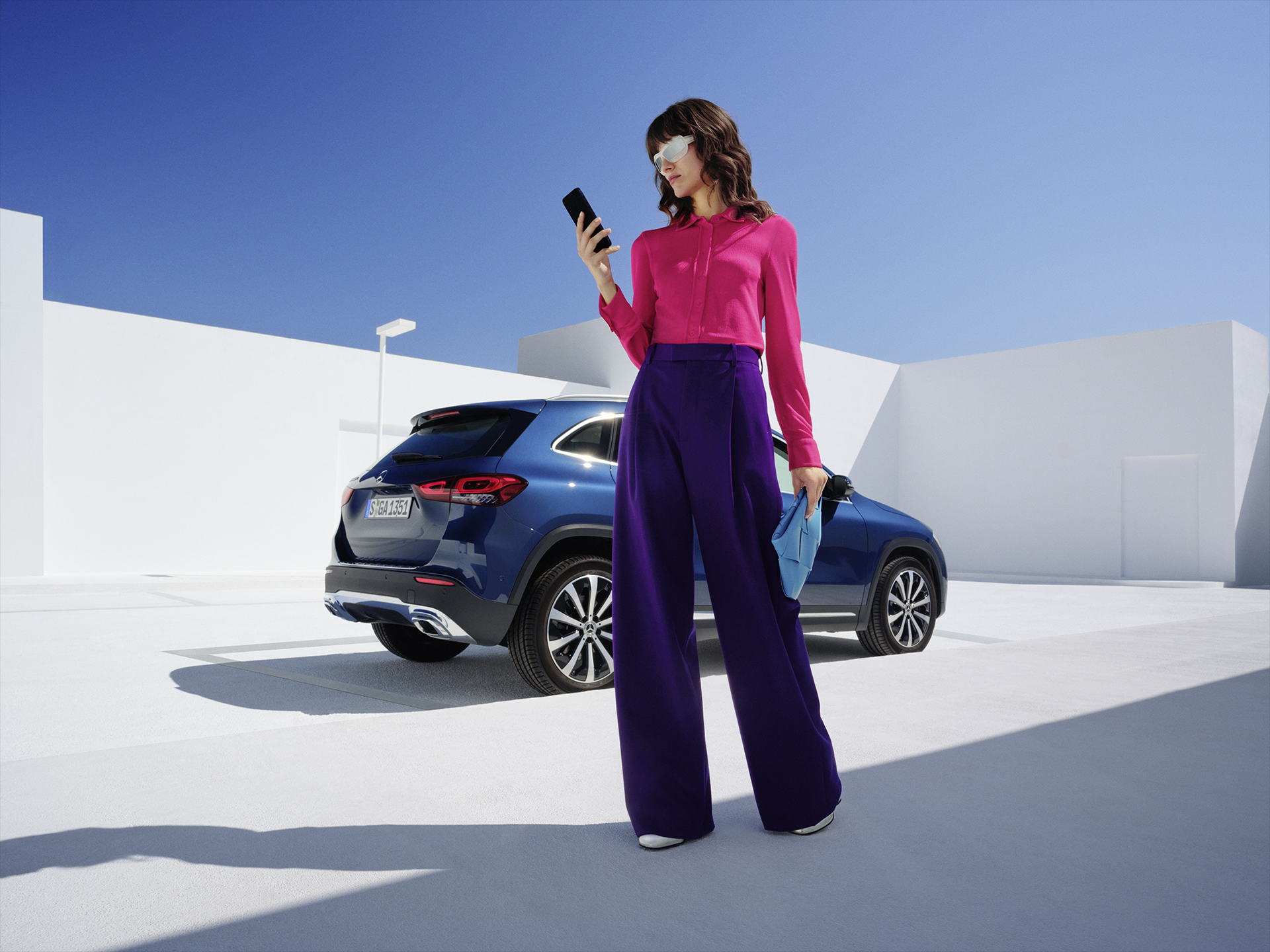 Mercedes me ID | Services connectés | Mercedes-Benz Une femme se tient devant la Mercedes-Benz GLA et consulte son téléphone.