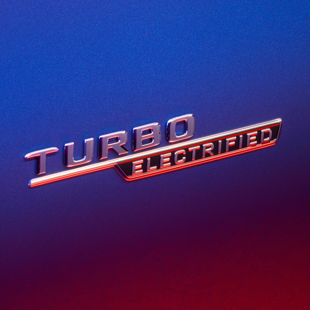 Targhetta TURBO E PERFORMANCE sui parafanghi anteriori, illuminata da una luce rossa.