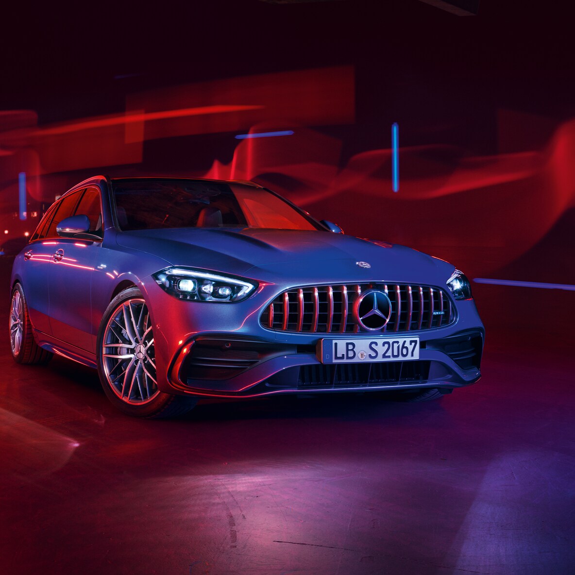Mercedes-AMG C 43 su vista frontale contro sfondo rosso.