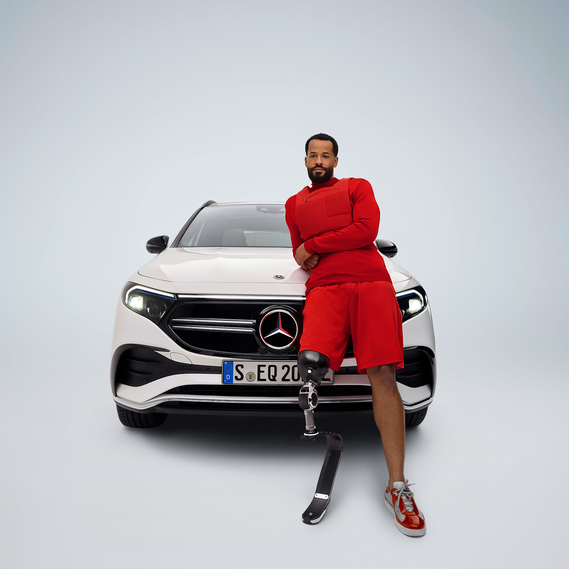 Adattamento dei pedali | Ausili alla guida | Mercedes-Benz Uomo con protesi alla gamba davanti a un Mercedes-Benz EQA.