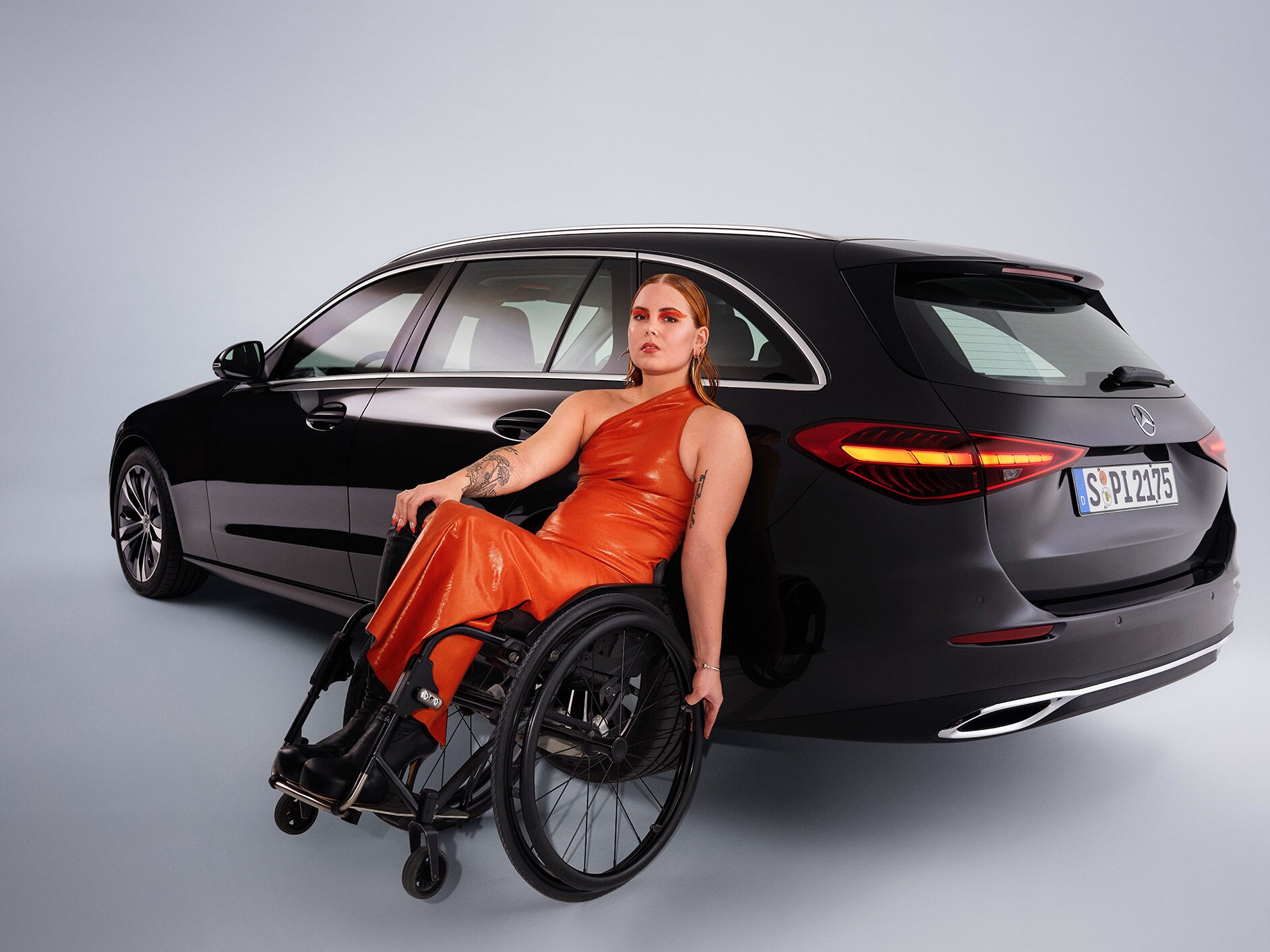 Un véhicule adapté aux personnes à mobilité réduite : la Classe C Break dans une vue de 3/4 arrière et une femme en fauteuil roulant.