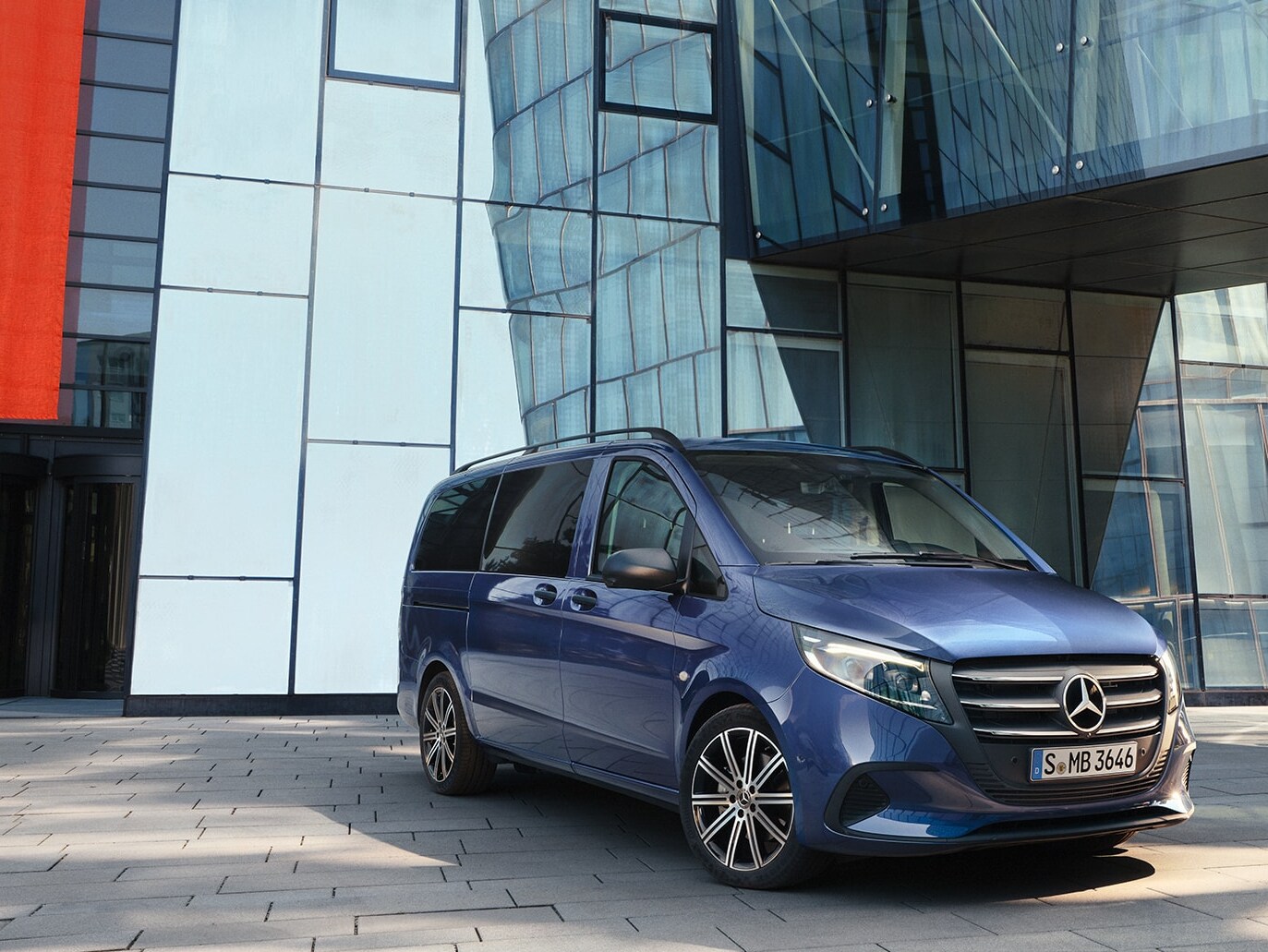 Ein Mercedes‑Benz Vito Tourer mit Schiebetür vor einem modernen Gebäude.