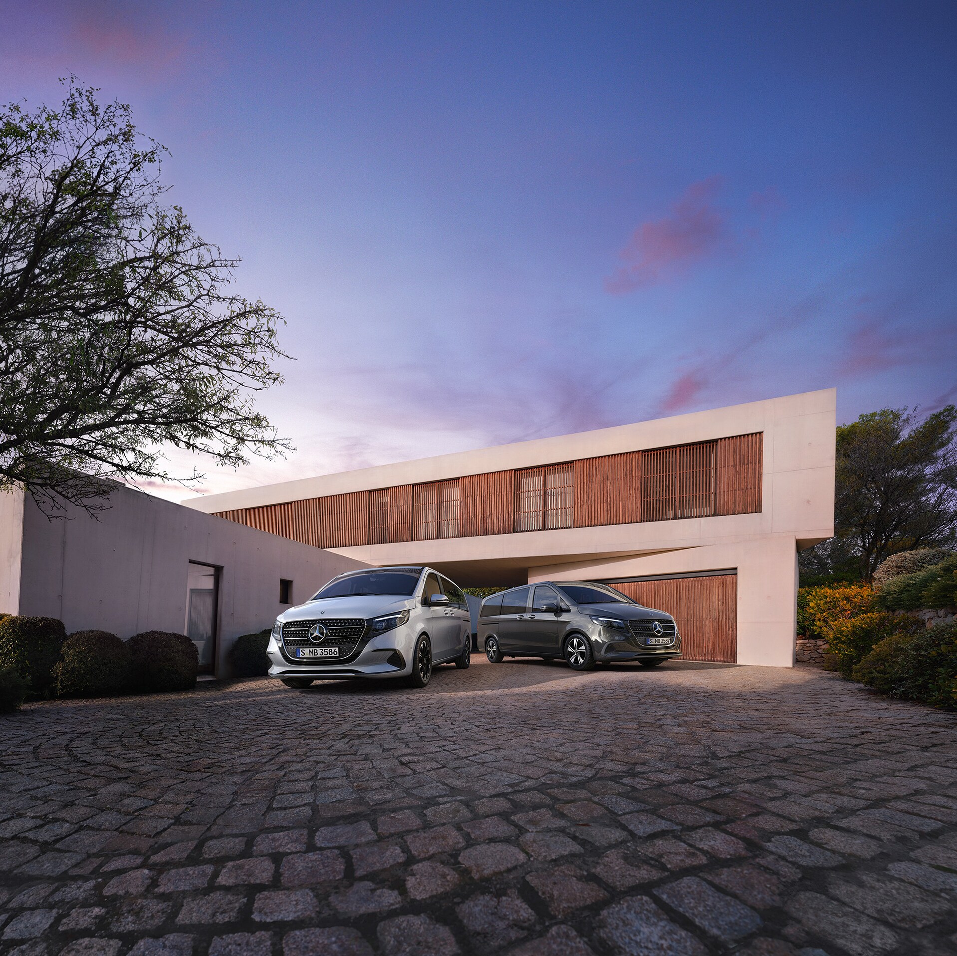 Eine Mercedes-Benz V-Klasse vor einem modernen Luxushaus in der Abenddämmerung.