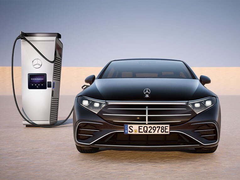 La berline EQS de Mercedes-Benz vue de face en charge sur une borne de recharge publique.