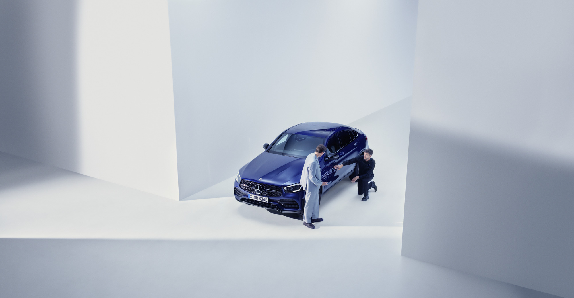 Schaden und Panne | Mercedes-Benz Mann vom Mercedes-Benz Support-Team kniet neben einem beschädigten Mercedes-Benz