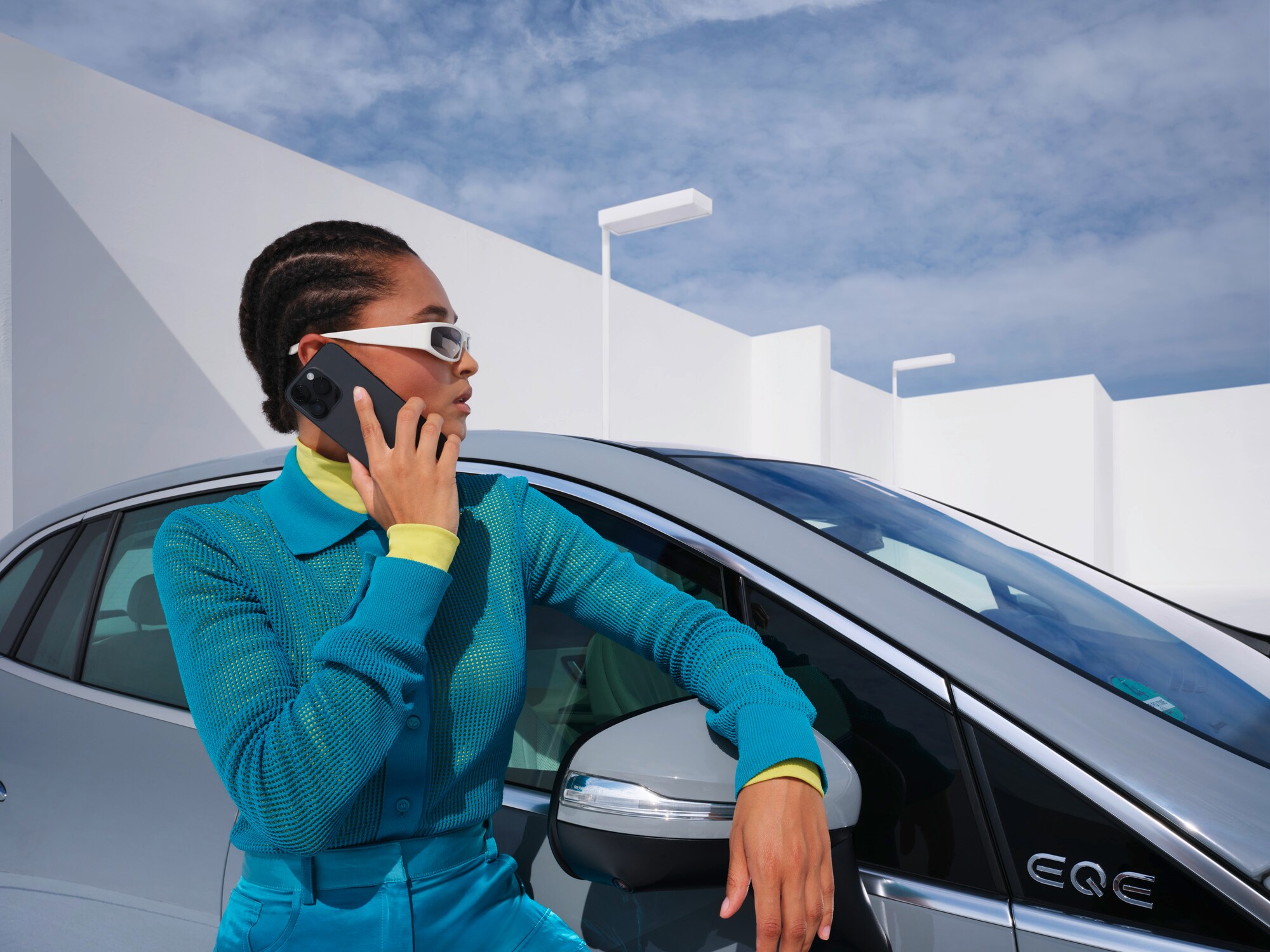 Une personne s'appuyant sur un véhicule Mercedes-Benz, le téléphone à la main.