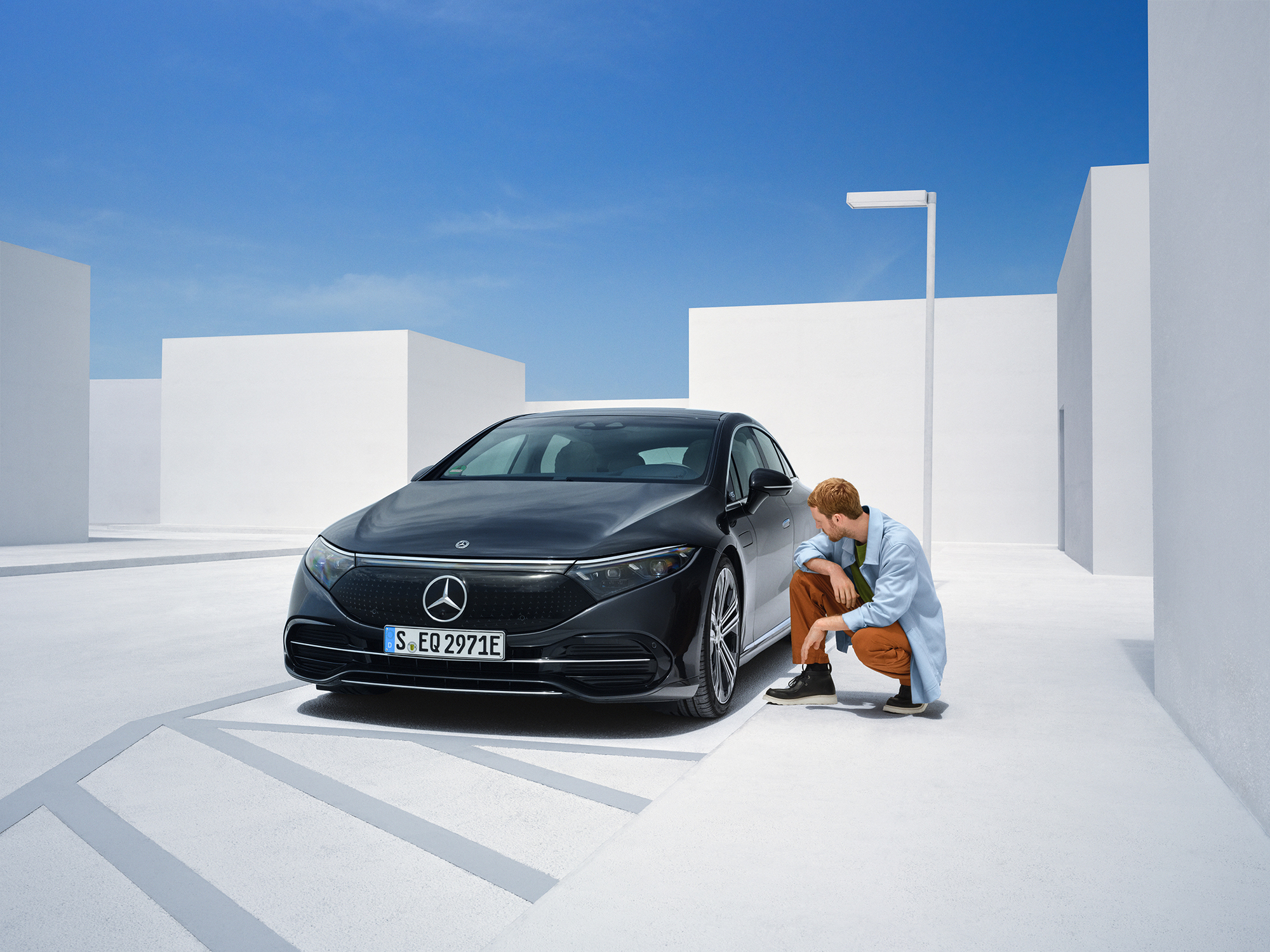 Segnalazione del danno | Mercedes-Benz Un uomo è inginocchiato a lato della sua Mercedes-Benz per controllarla