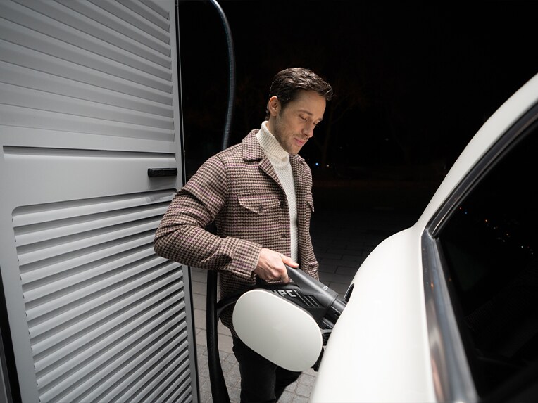 Un homme rechargeant sa voiture électrique Mercedes-Benz sur une borne de recharge.