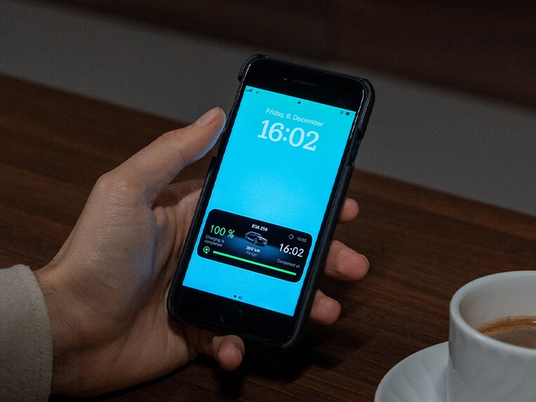 Un homme tenant un smartphone avec l'application Mercedes-Benz.