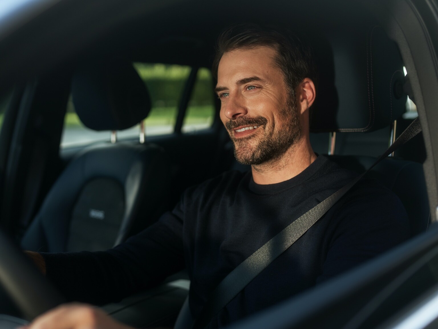 Ein Mann genießt in seinem Mercedes-Benz dank des Entertainment-Pakets unterbrechungsfreies Internetradio.