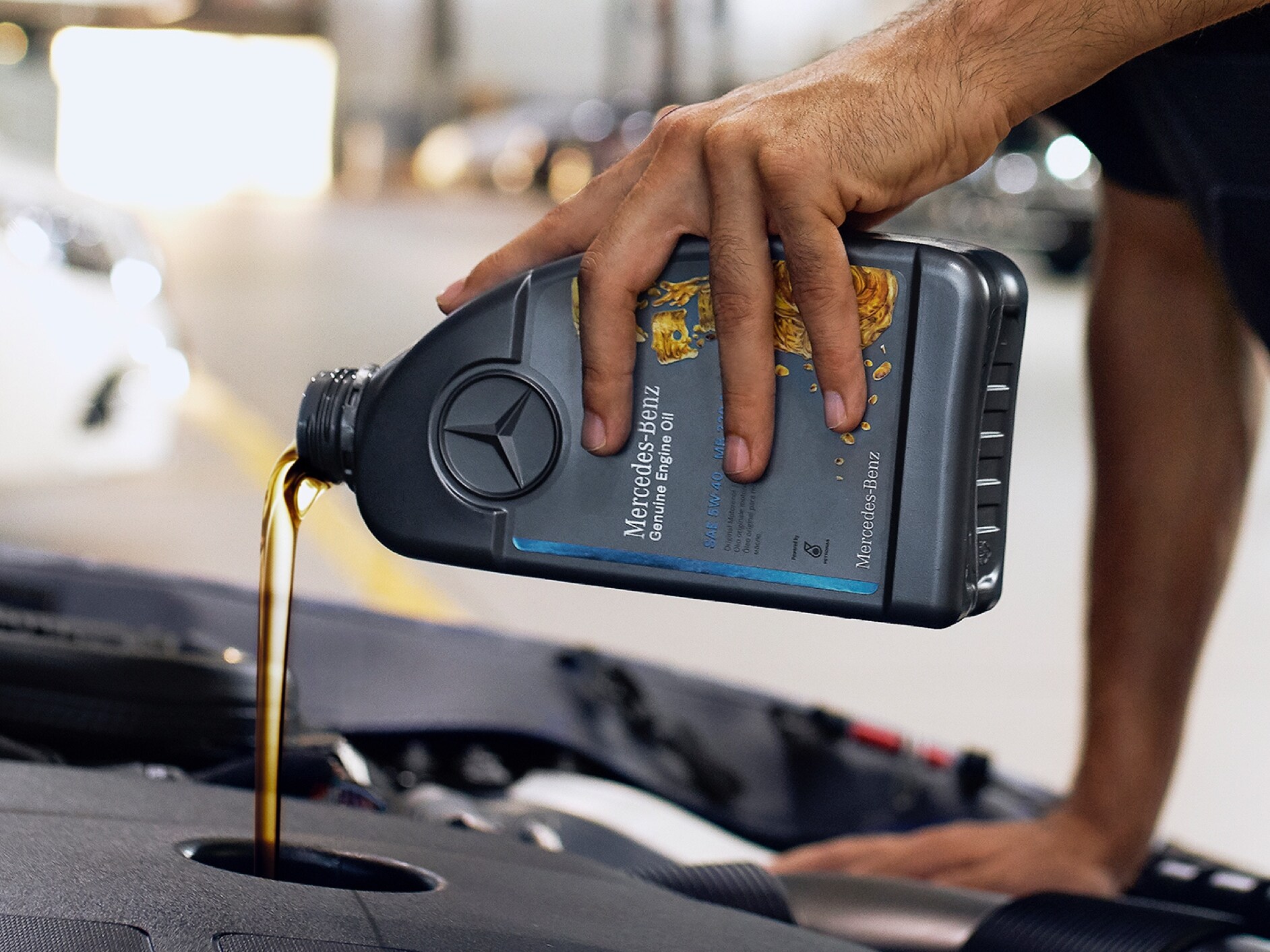 A person pouring engine oil into the Mercedes-Benz vehicle.