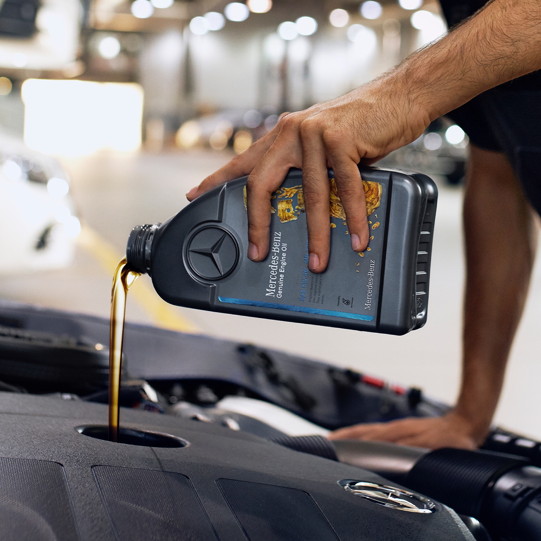 Olio motore | Mercedes-Benz Una persona mentre versa l'olio motore nel veicolo Mercedes-Benz.