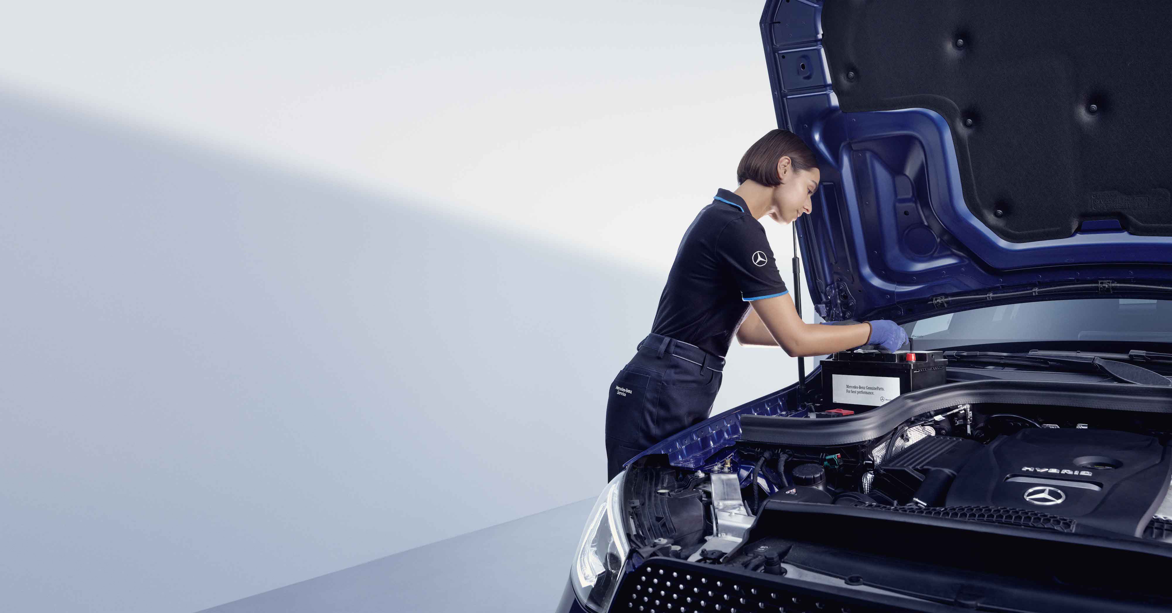 Genuine Parts | Mercedes-Benz A automotive mechanic bends over the open bonnet of a Mercedes-Benz.