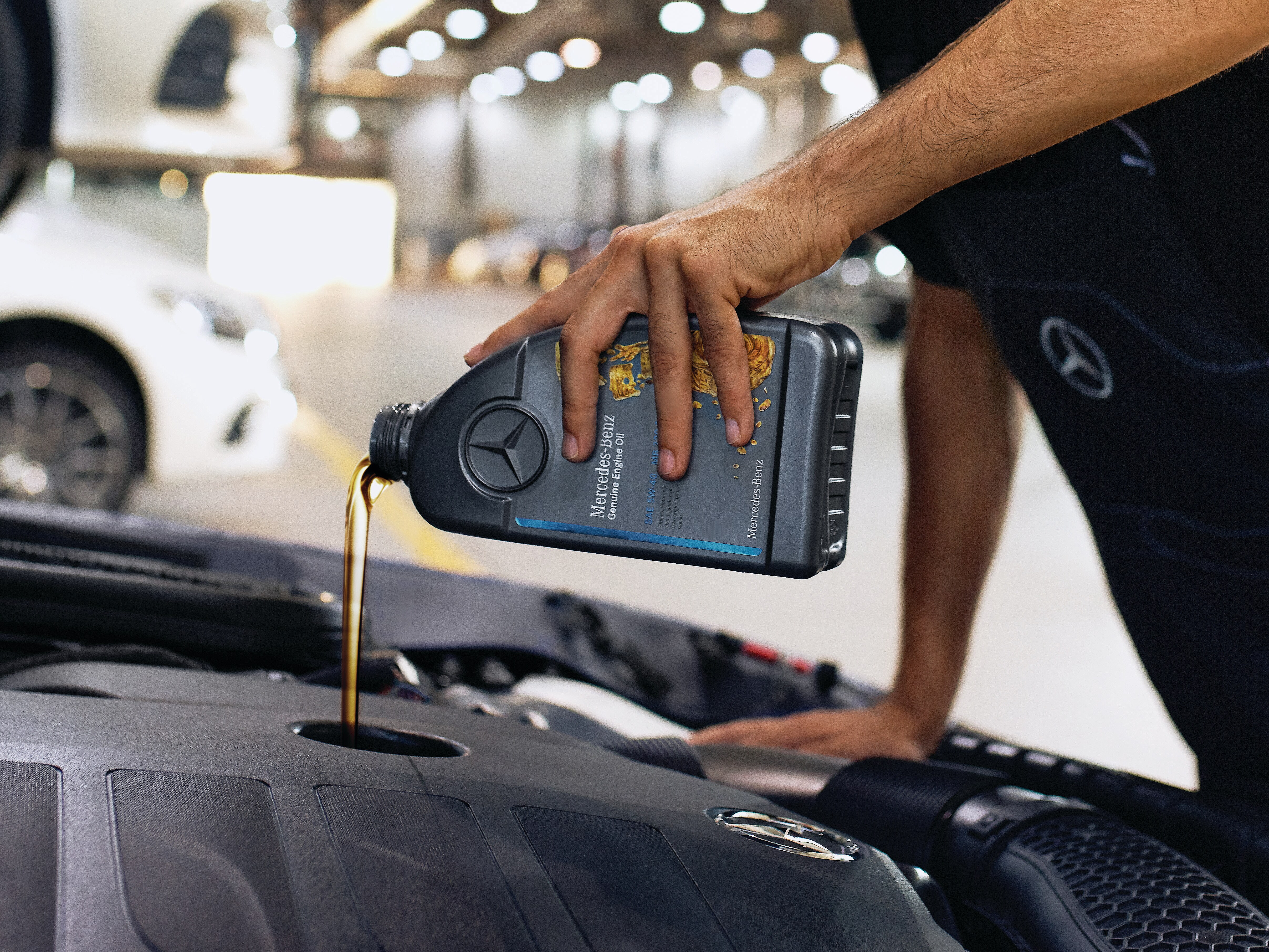 Gros plan sur le compartiment moteur pendant le remplissage avec de l'huile moteur d'origine Mercedes-Benz.