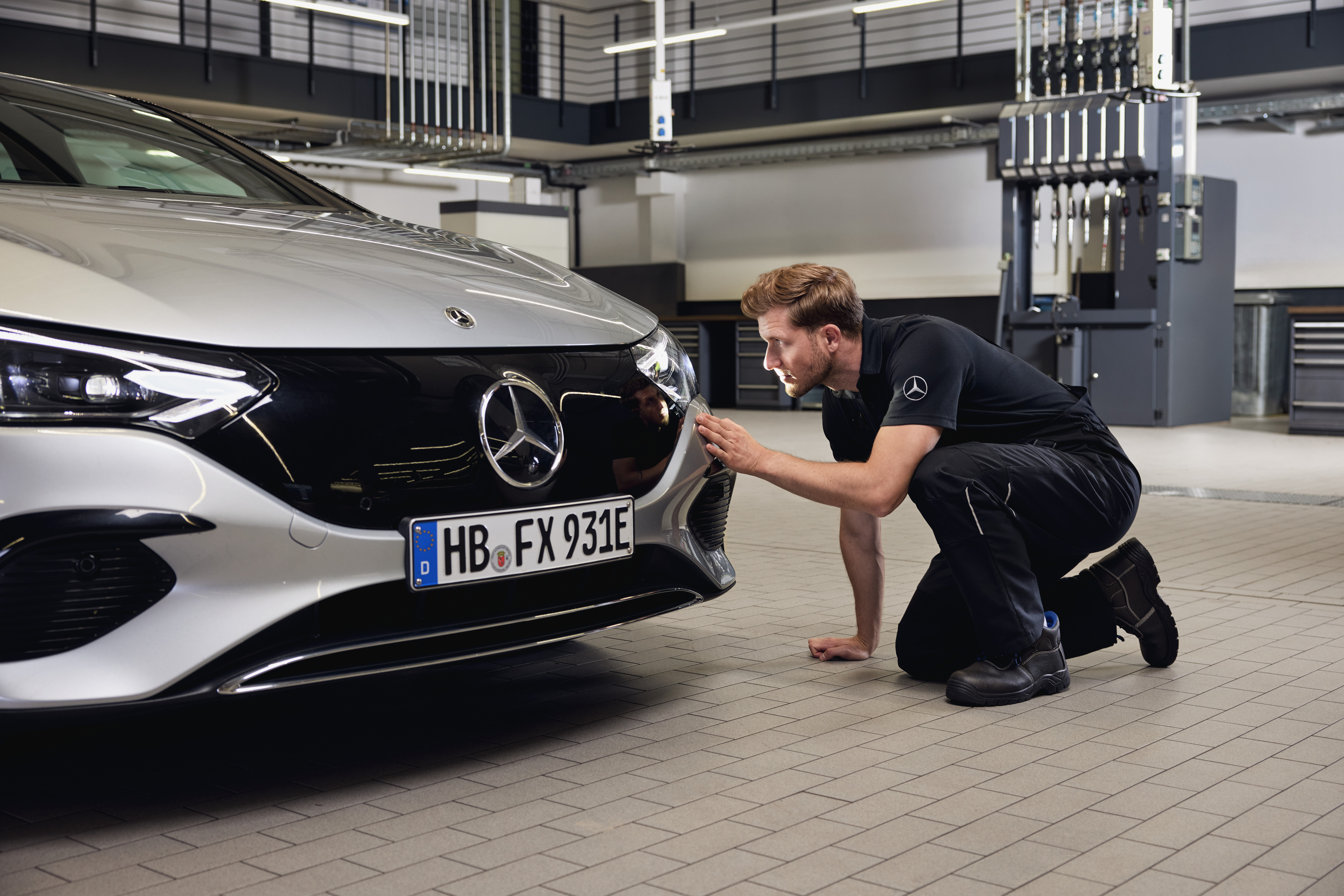 Sostituzione dei fari originali Mercedes-Benz Primo piano del frontale di un veicolo Mercedes-Benz; un tecnico esegue un esame dettagliato per effettuare la sostituzione dei componenti originali Mercedes-Benz.