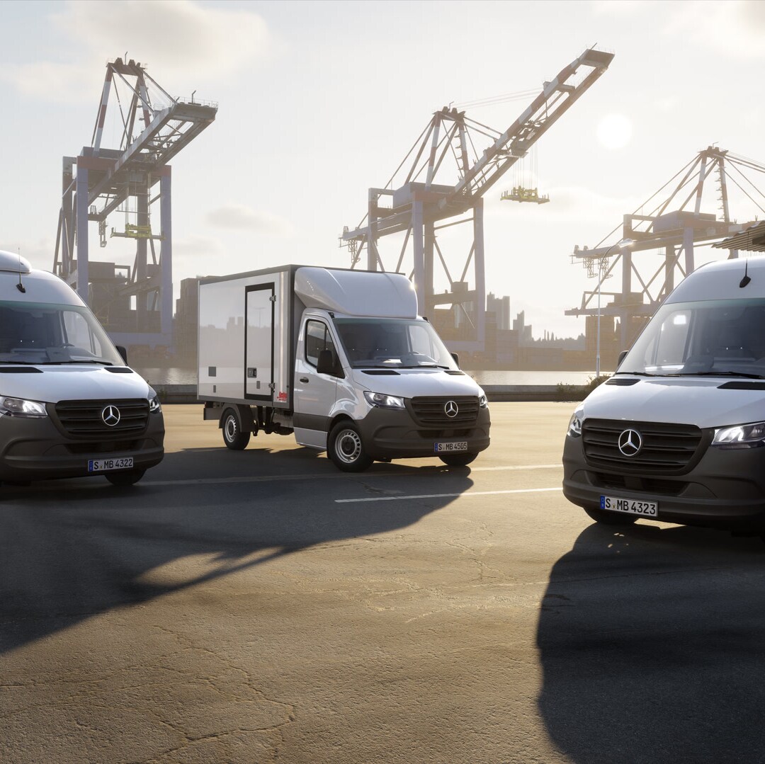 Tre veicoli commerciali Mercedes-Benz tra container e gru portuali.
