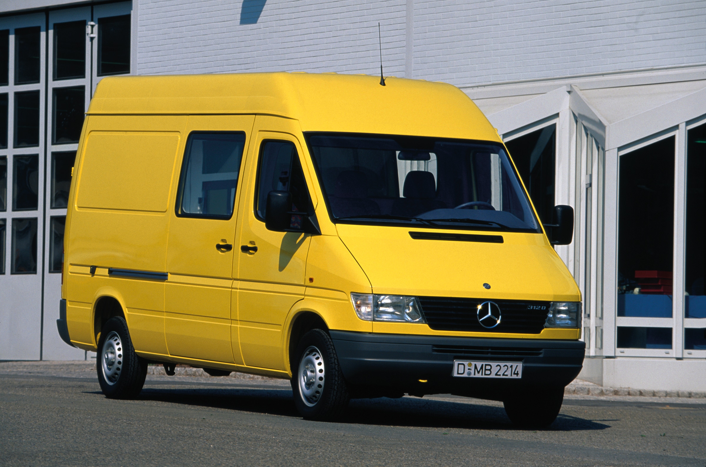 La première génération de Sprinter Mercedes-Benz | Histoire des véhicules industriels | Mercedes-Benz Un Sprinter de première génération garé devant un bâtiment industriel