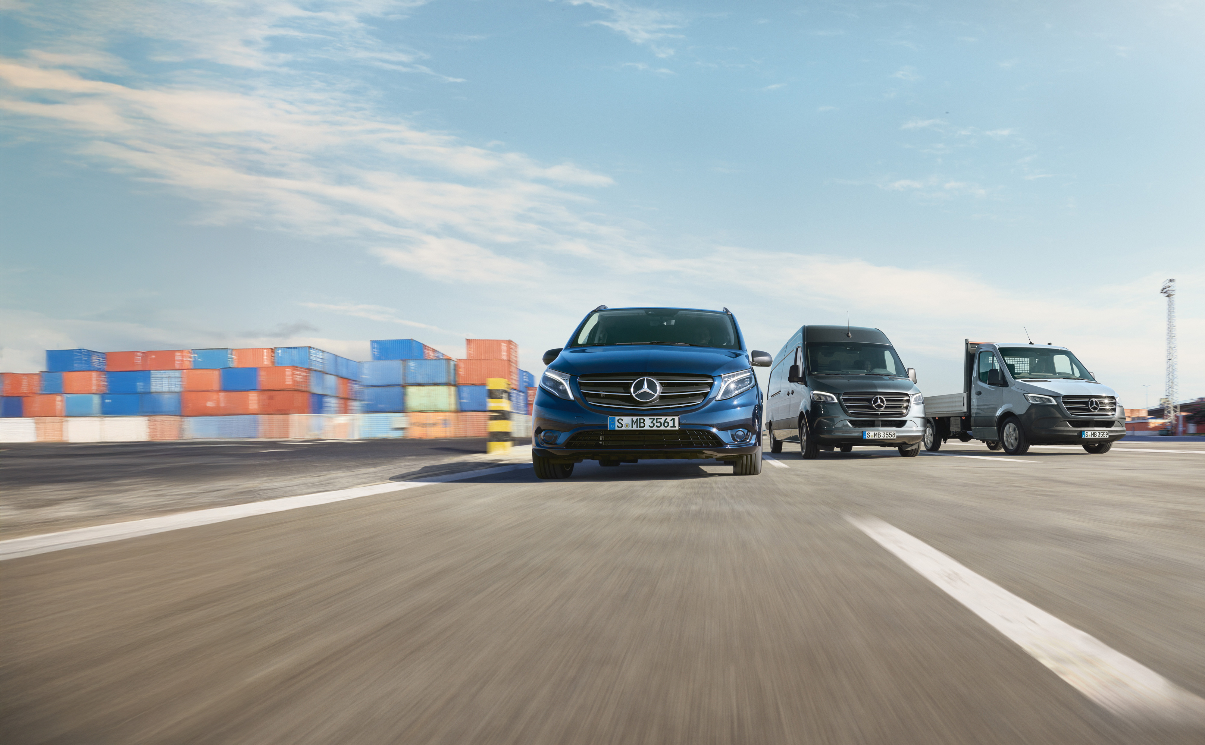 Mercedes-Benz | Maintenance des utilitaires légers | Service24h Une série d’utilitaires légers Mercedes-Benz garés côte à côte sur une route à côté d'un quai d'expédition.