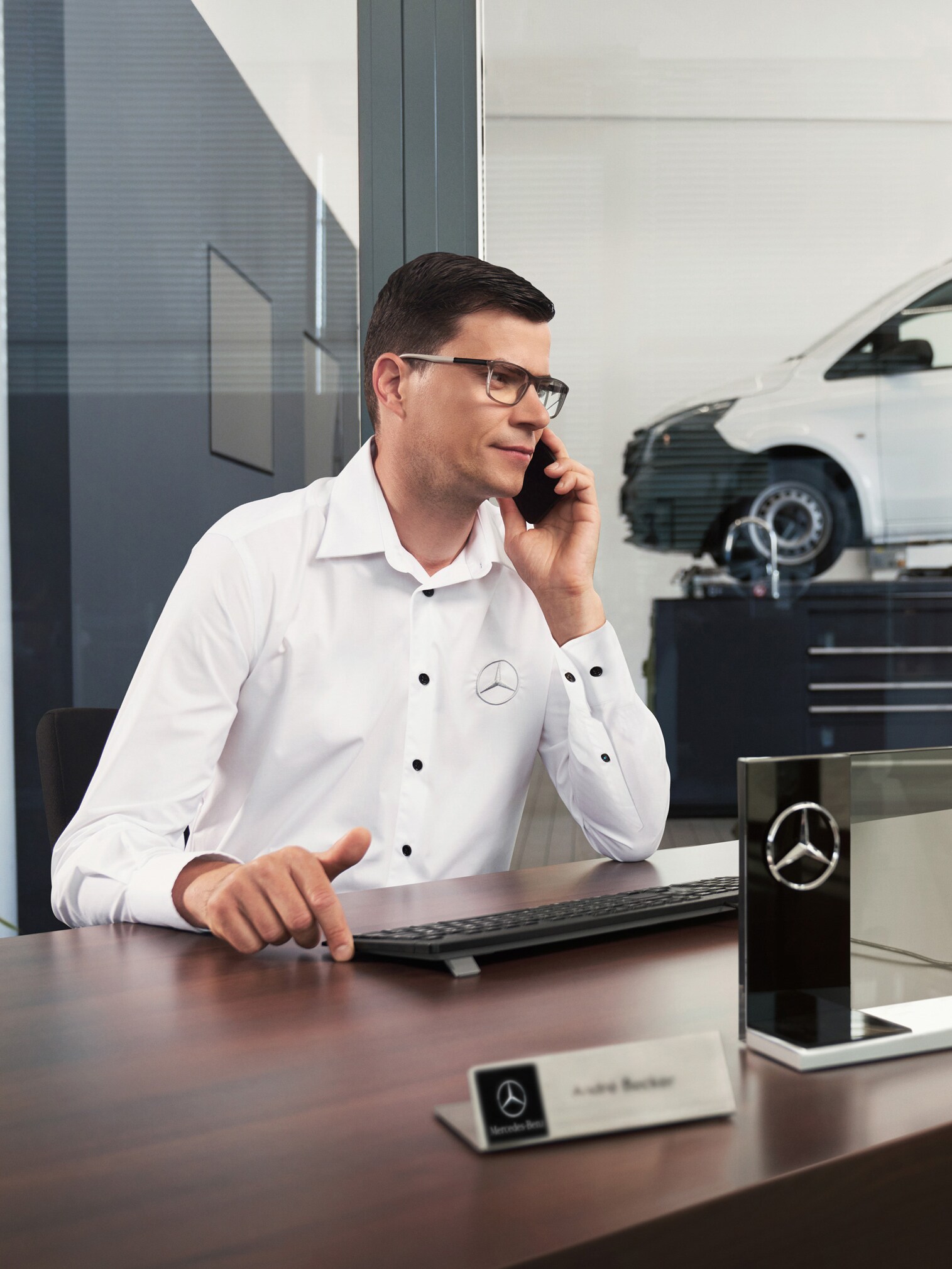 Un dipendente Mercedes-Benz mentre parla al telefono seduto a una scrivania.