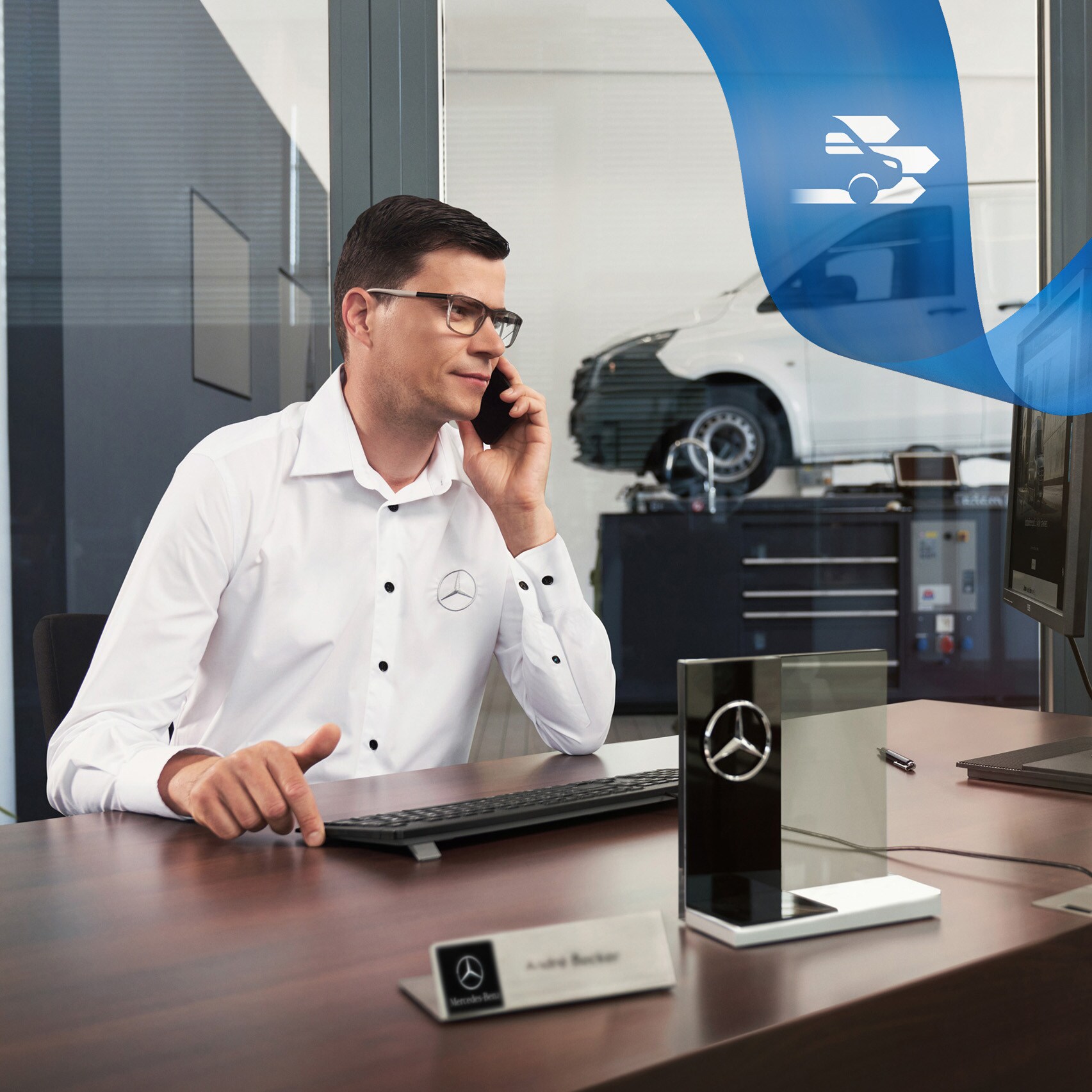 Un employé au téléphone et une utilitaire léger Mercedes-Benz Vito dans l'atelier à l'arrière-plan.