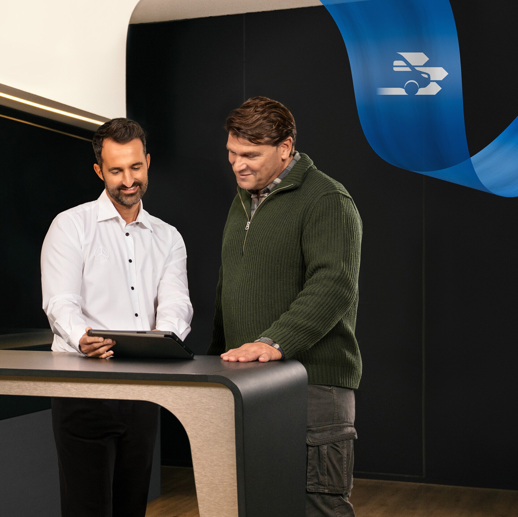 Zwei Männer stehen im Büro eines Mercedes-Benz Service-Partners und diskutieren über etwas, das sie auf einem Tablet gesehen haben