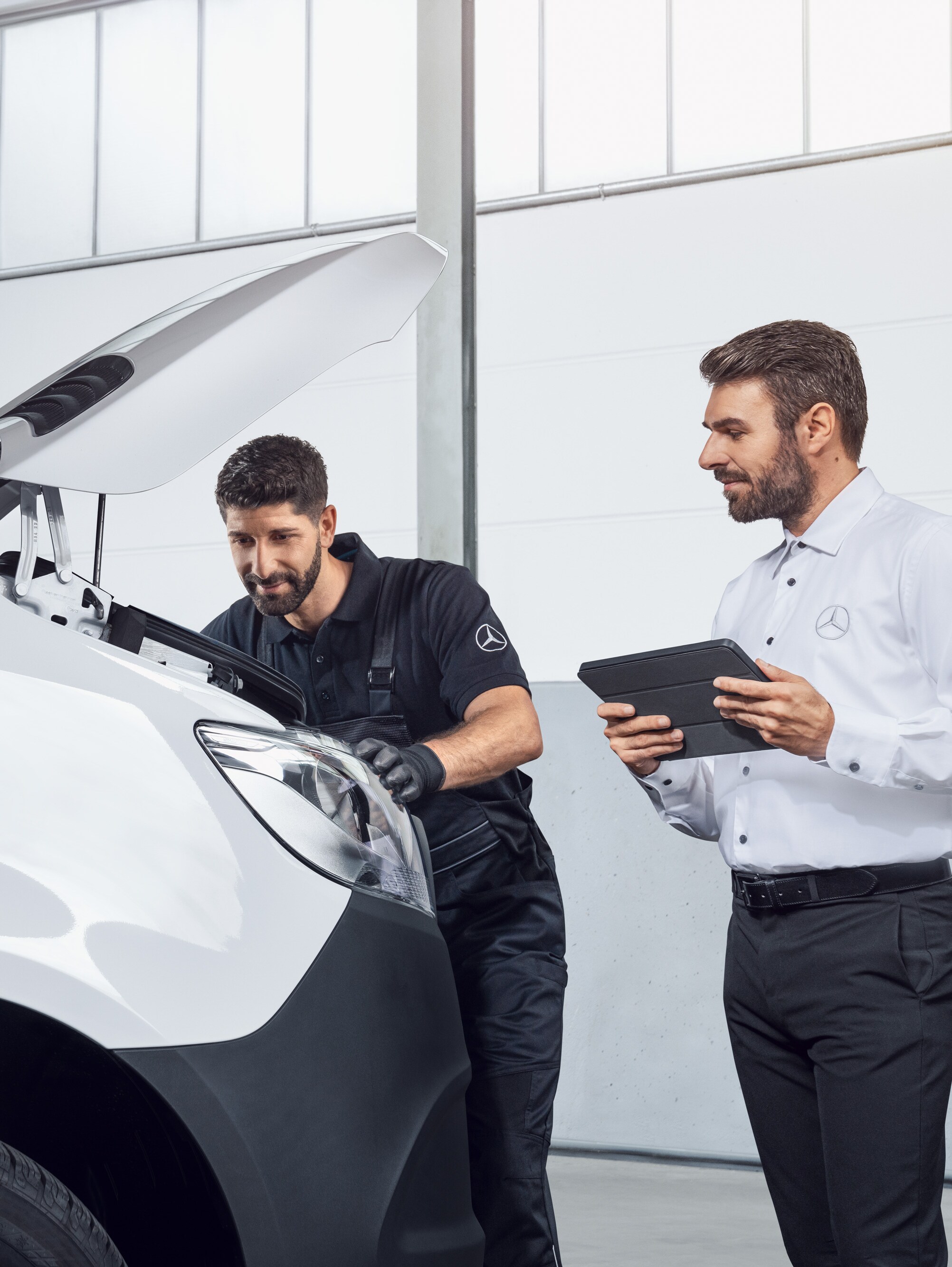 Due uomini mentre testano un Mercedes Sprinter con tablet e cofano aperto, argomento: ricambi per il Mercedes-Benz Sprinter.