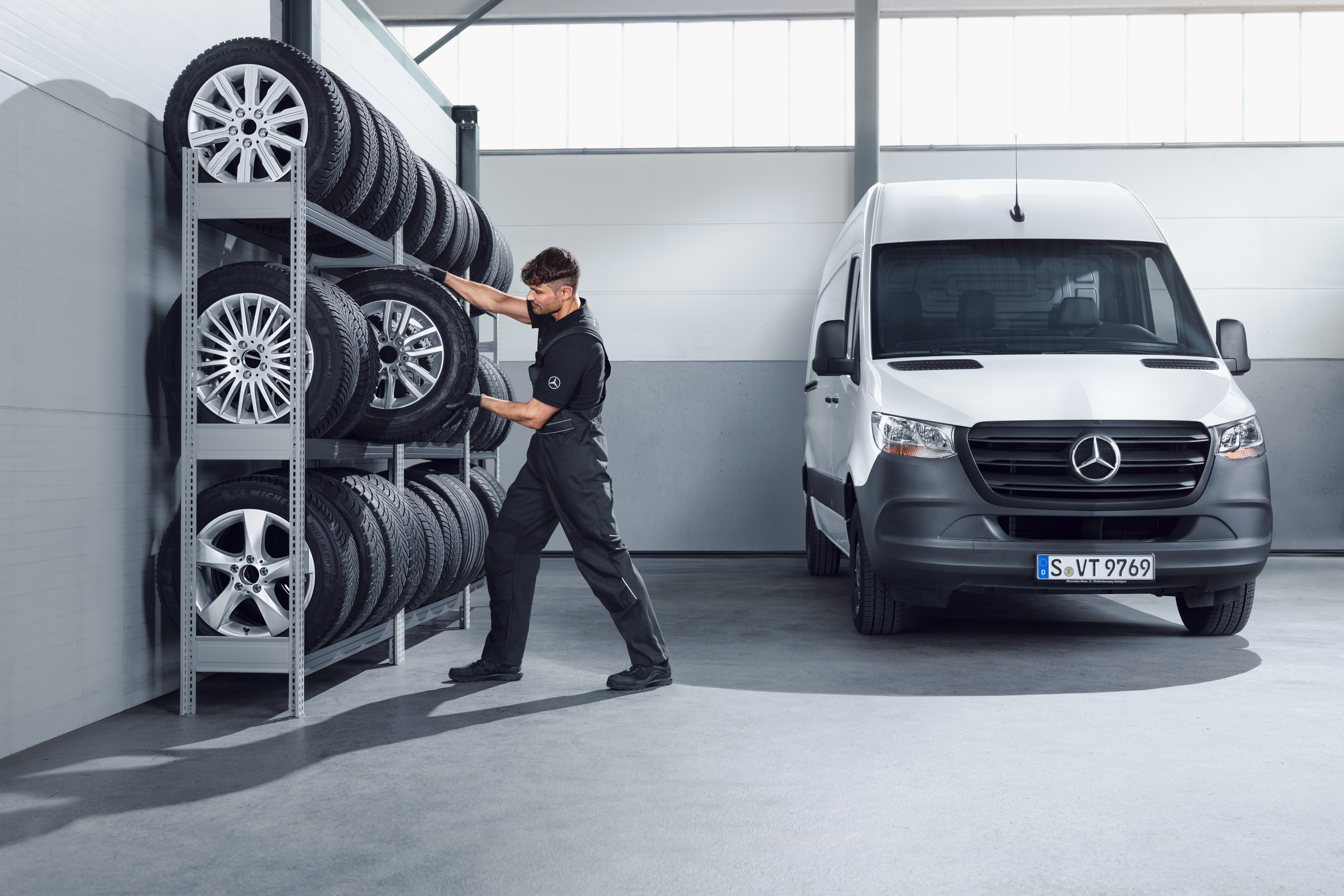 Mercedes-Benz | Transporter Qualität Original-Teile Mechaniker sucht Mercedes-Benz Winterkompletträder für einen weißen Sprinter aus dem Werkstattregal aus.