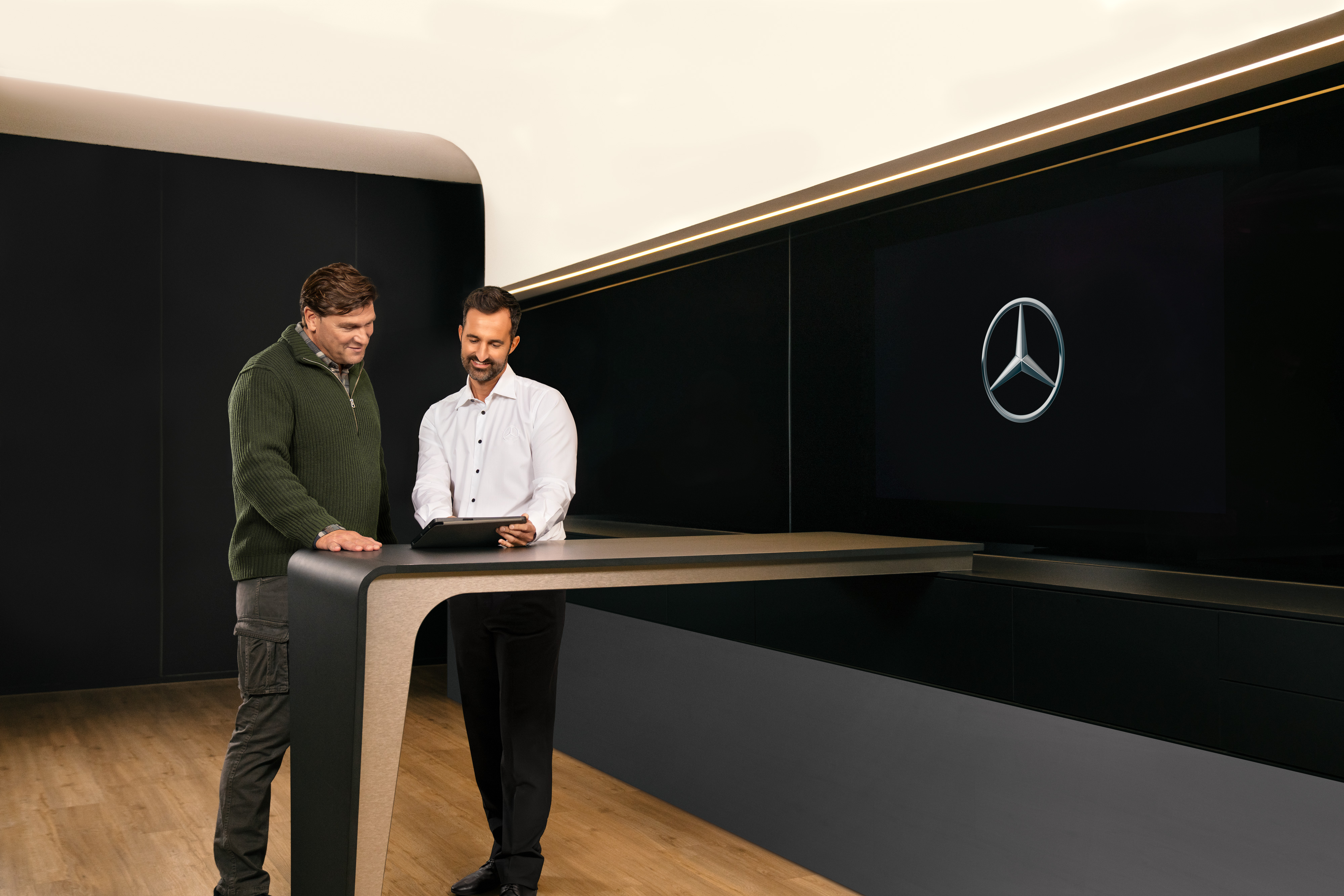 Mercedes-Benz | Serviceübersicht | ServiceCare Zwei Männer diskutieren über ein Tablet über den Nutzfahrzeugservice von Mercedes-Benz.