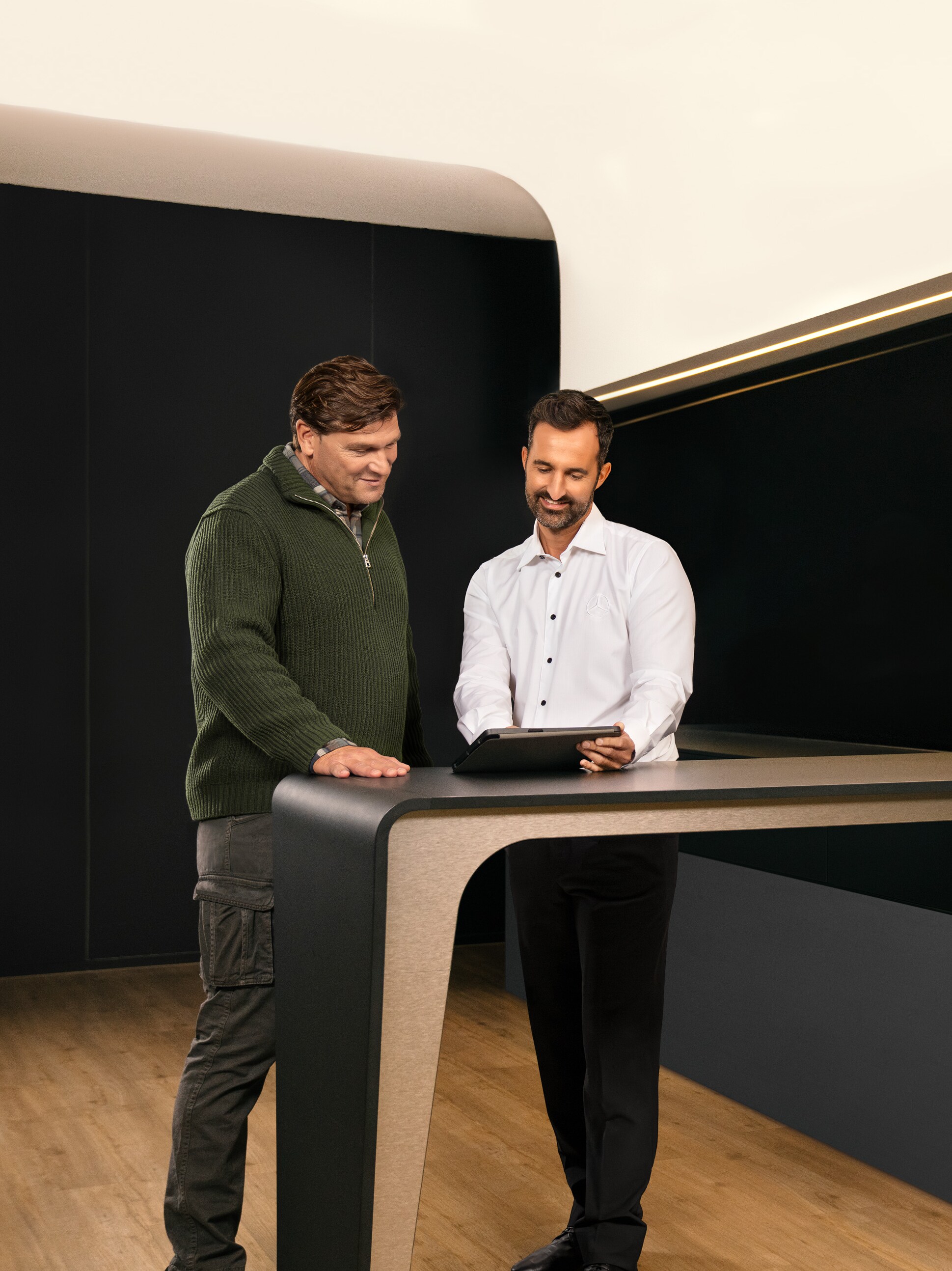 Due uomini discutono del servizio assistenza dei veicoli commerciali Mercedes-Benz davanti a un tablet.