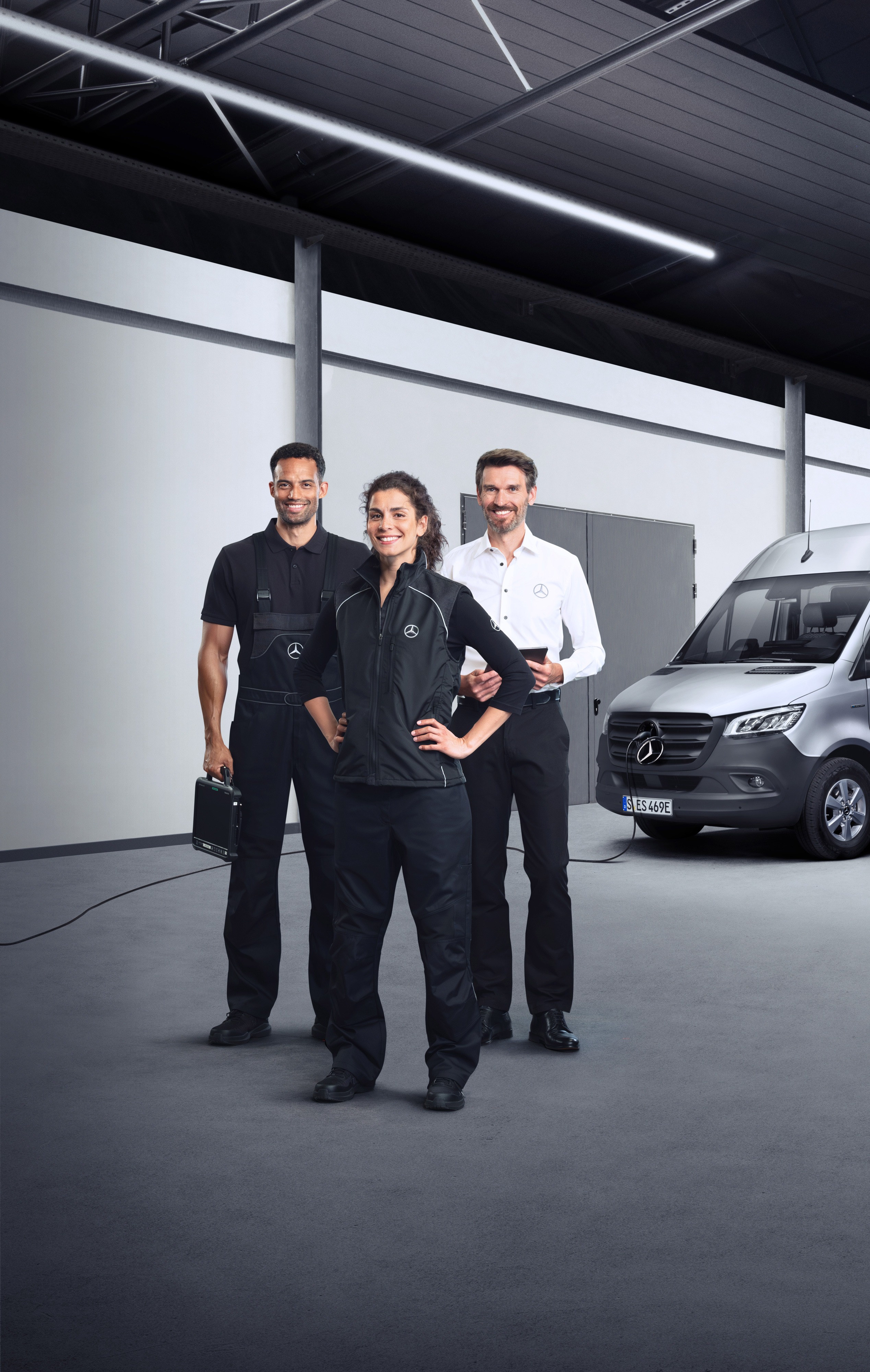 Mercedes-Benz | Dienstleistungen im Überblick | Services für Elektro-Transporter Drei Mitarbeiter stehen vor einem silbernen Mercedes-Benz eSprinter mit angeschlossenem Ladekabel.