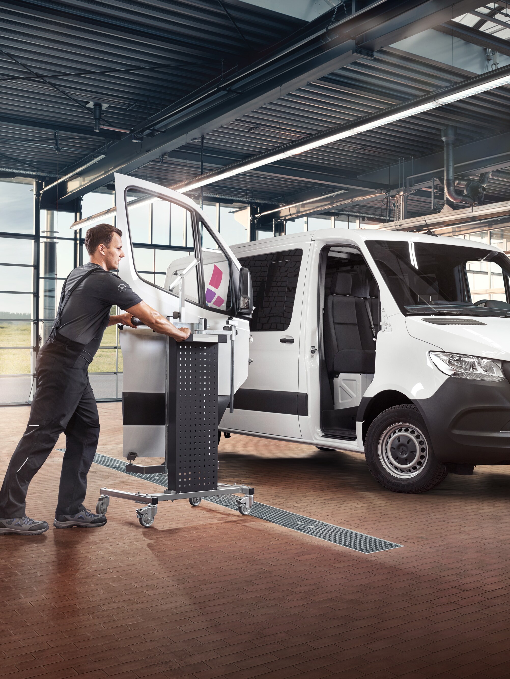 Ein Techniker wartet die Beifahrertür eines weißen Mercedes-Benz Sprinter Transporters.