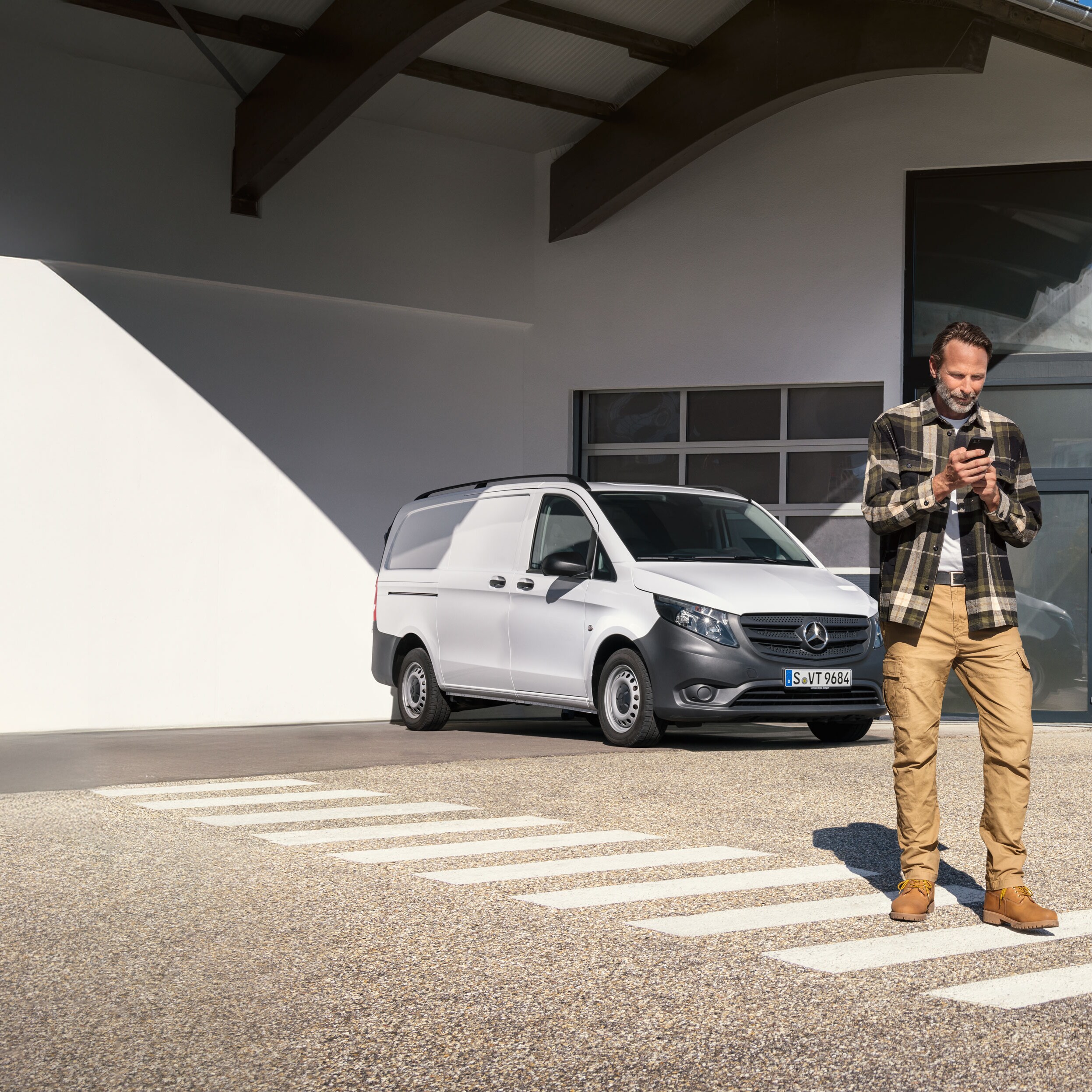 Customer books an appointment using his mobile device while standing infront of a white Mercedes-Benz Vito van.