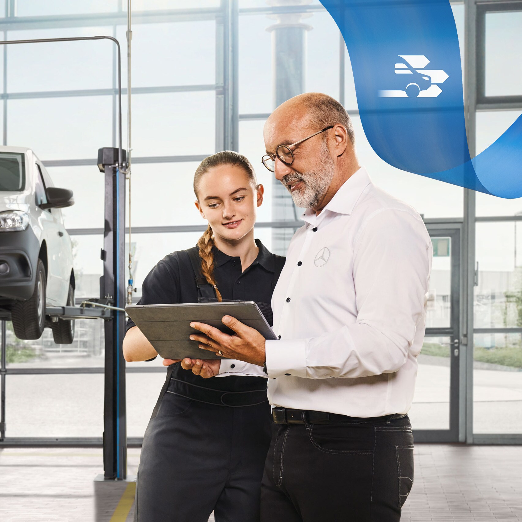 Zwei Mitarbeiter besprechen in der Werkstatt den Nutzfahrzeugservice an einem aufgebockten Mercedes-Benz Transporter.