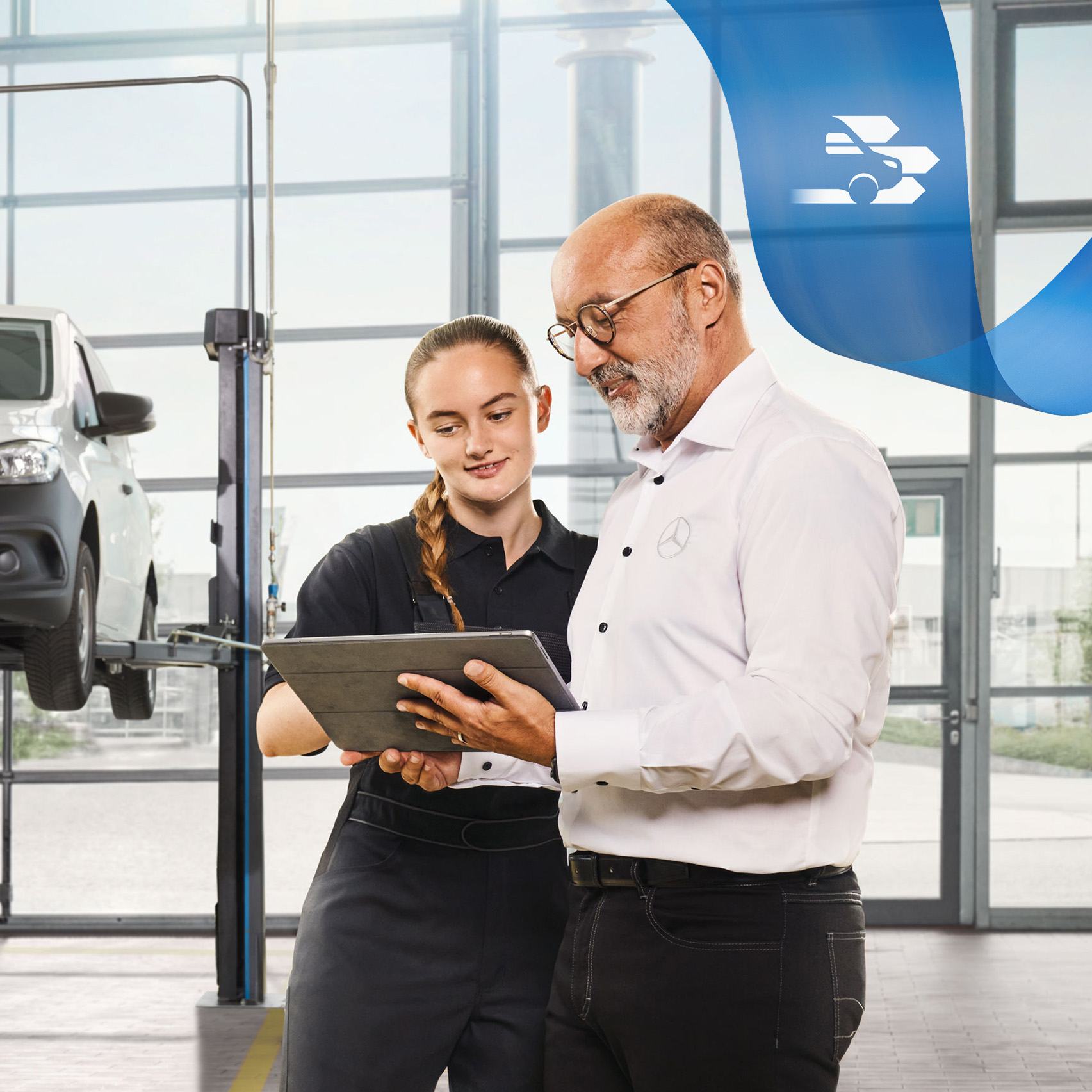 Mercedes-Benz | Wartung Zwei Mitarbeiter besprechen in der Werkstatt den Nutzfahrzeugservice an einem aufgebockten Mercedes-Benz Transporter.