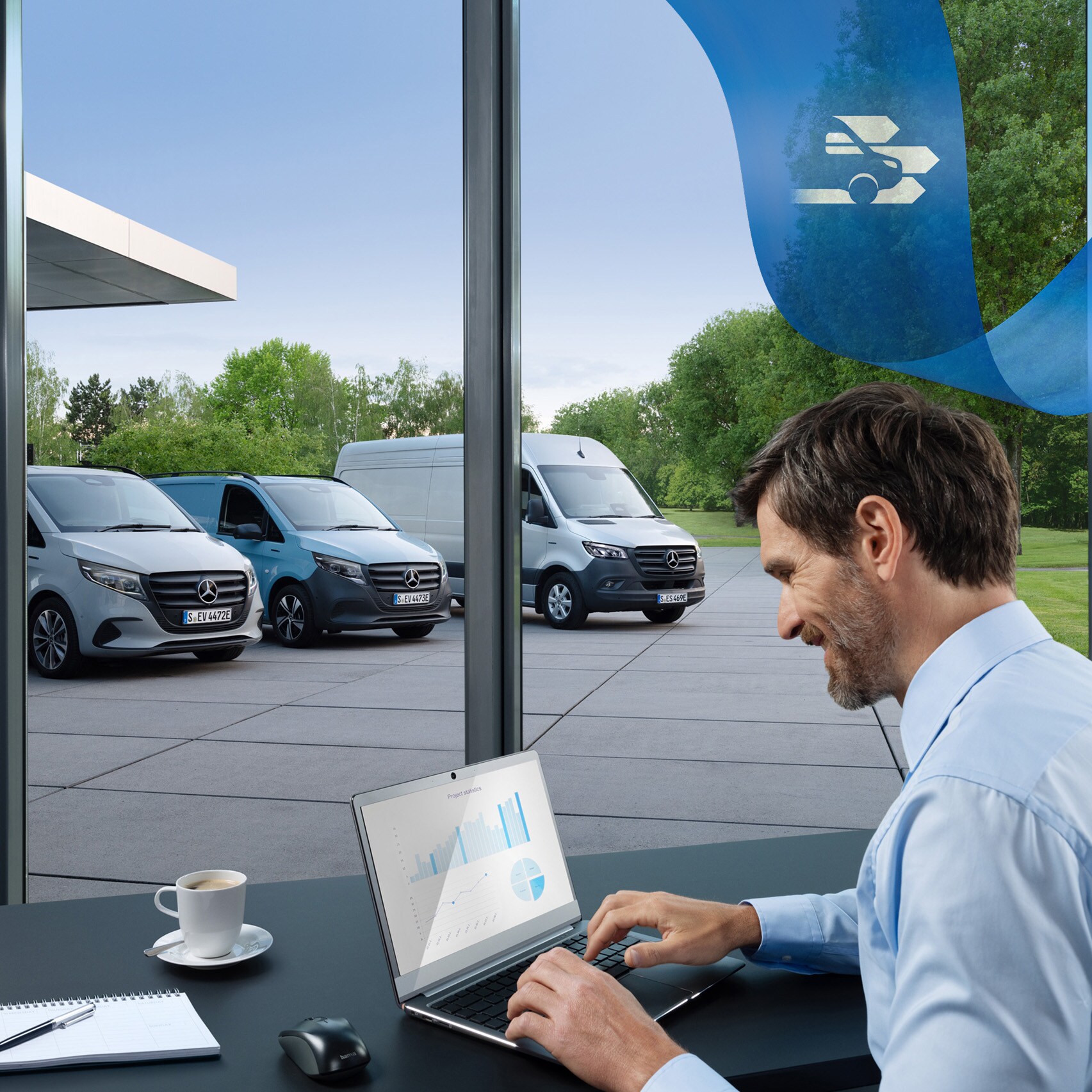 Un homme utilisant un ordinateur portable dans un bureau avec une série d’utilitaires légers Mercedes-Benz en arrière-plan.