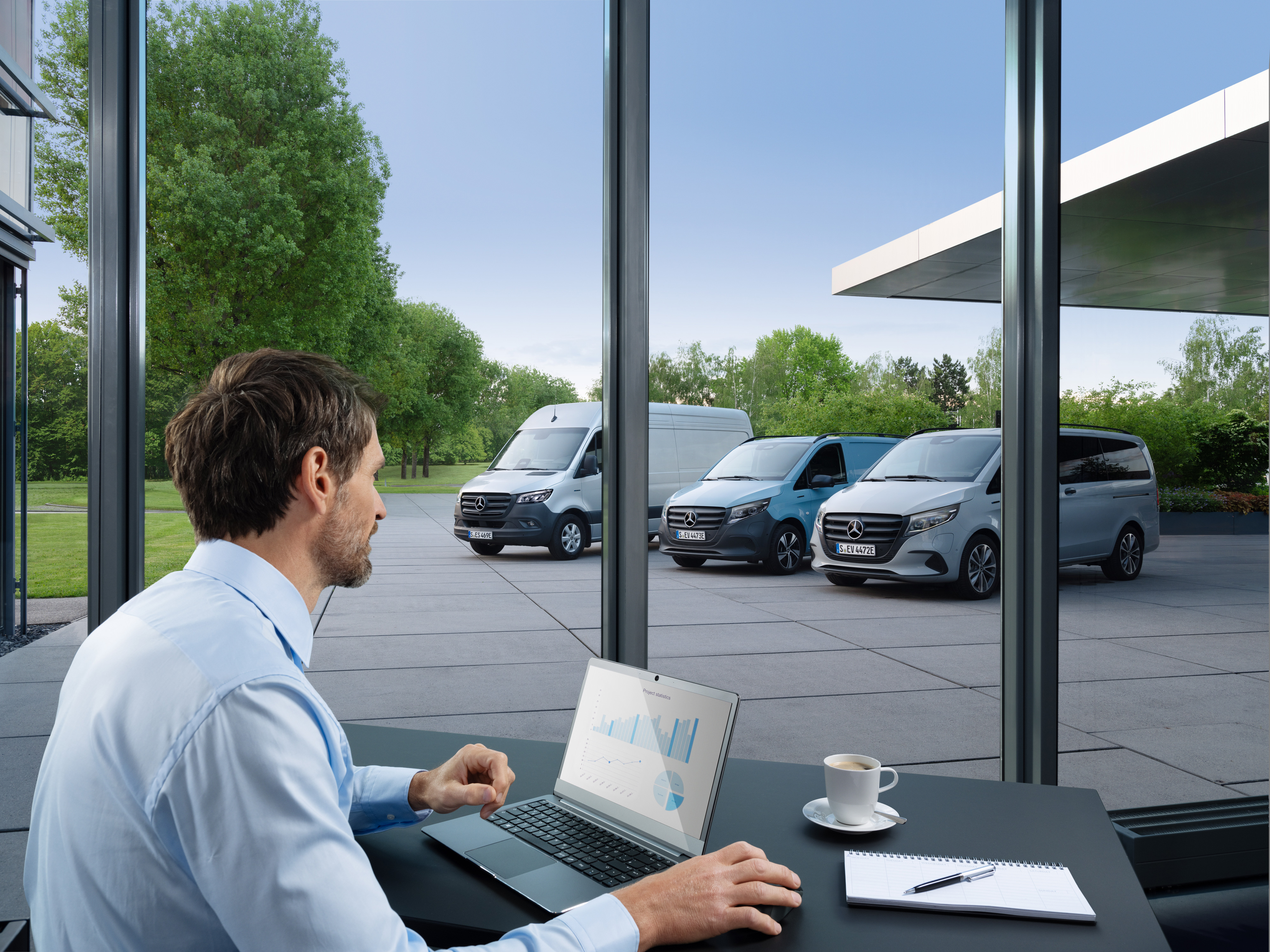 Mercedes-Benz | Tecnologia per veicoli commerciali | Van Uptime Monitor Un uomo controlla diversi veicoli commerciali Mercedes-Benz parcheggiati con un computer portatile, simbolo della gestione digitale della flotta.