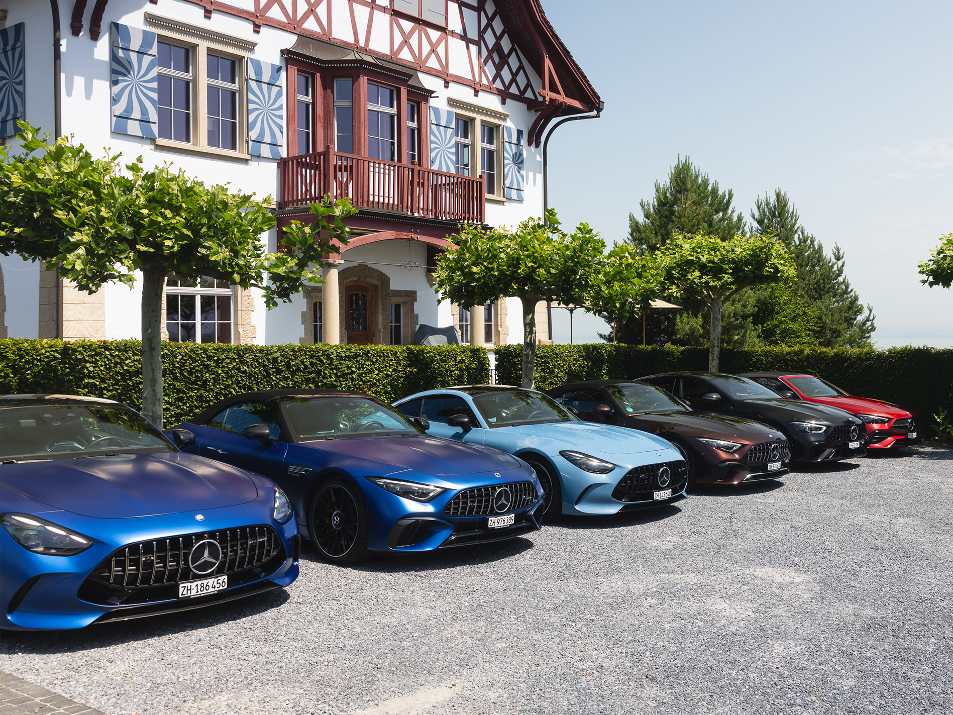 Die Mercedes-Benz Genusstour Mehrere Mercedes-Benz Fahrzeuge stehen in der Sonne auf einem Kiesplatz vor einem Restaurant.