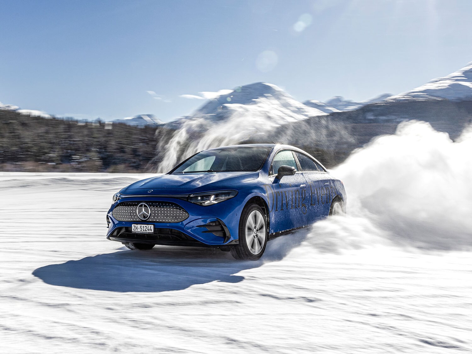 Una Mercedes-AMG blu scuro accelera sul circuito innevato sollevando della neve.
