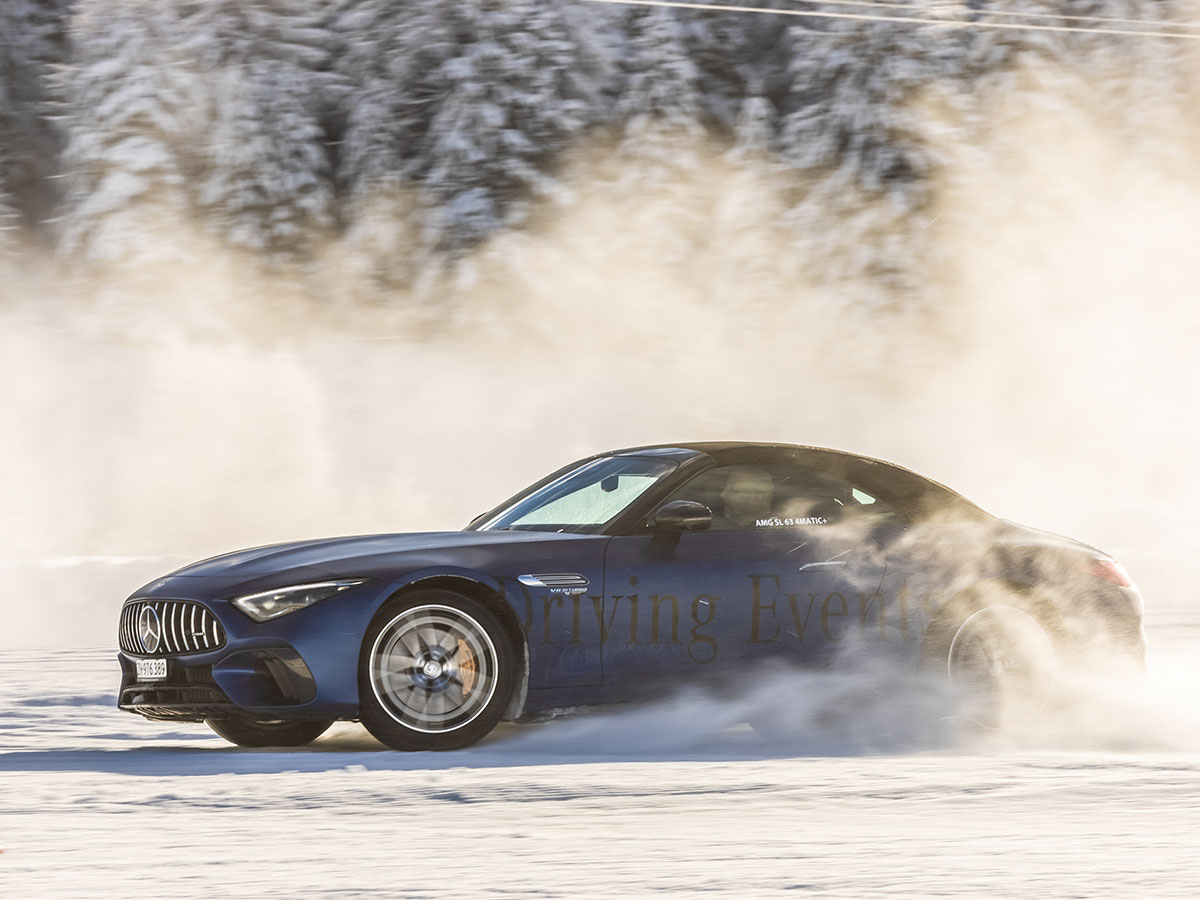 Le dynamisme sur la neige et la glace Une Mercedes-AMG bleu foncé accélère sur la piste enneigée en soulevant de la neige.