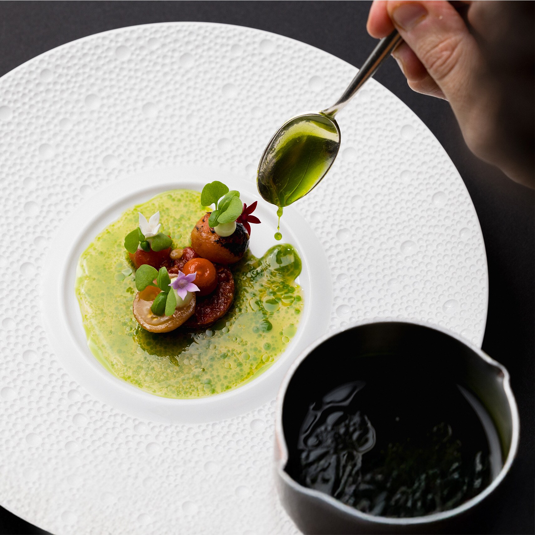 Piccola ed elegante portata su un piatto bianco, sapientemente guarnito con una salsa verde.