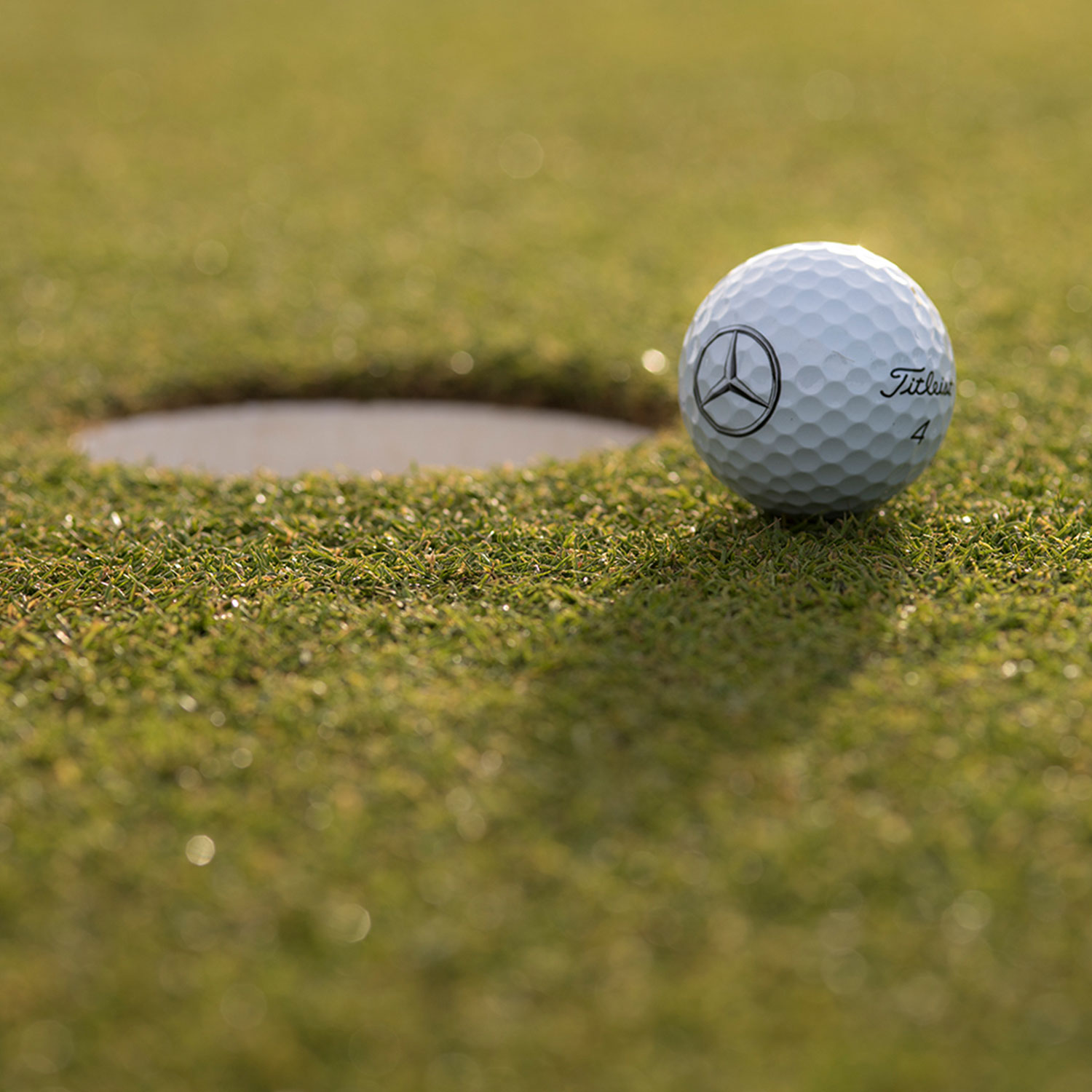 MercedesTrophy Swiss Final Une balle de golf avec le logo Mercedes-Benz se trouve juste avant le trou sur un green tondu.