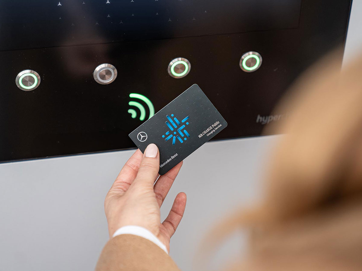 Carta di ricarica di MB.CHARGE Public Donna tiene una carta di ricarica di MB.CHARGE Public davanti a un display della colonnina di ricarica