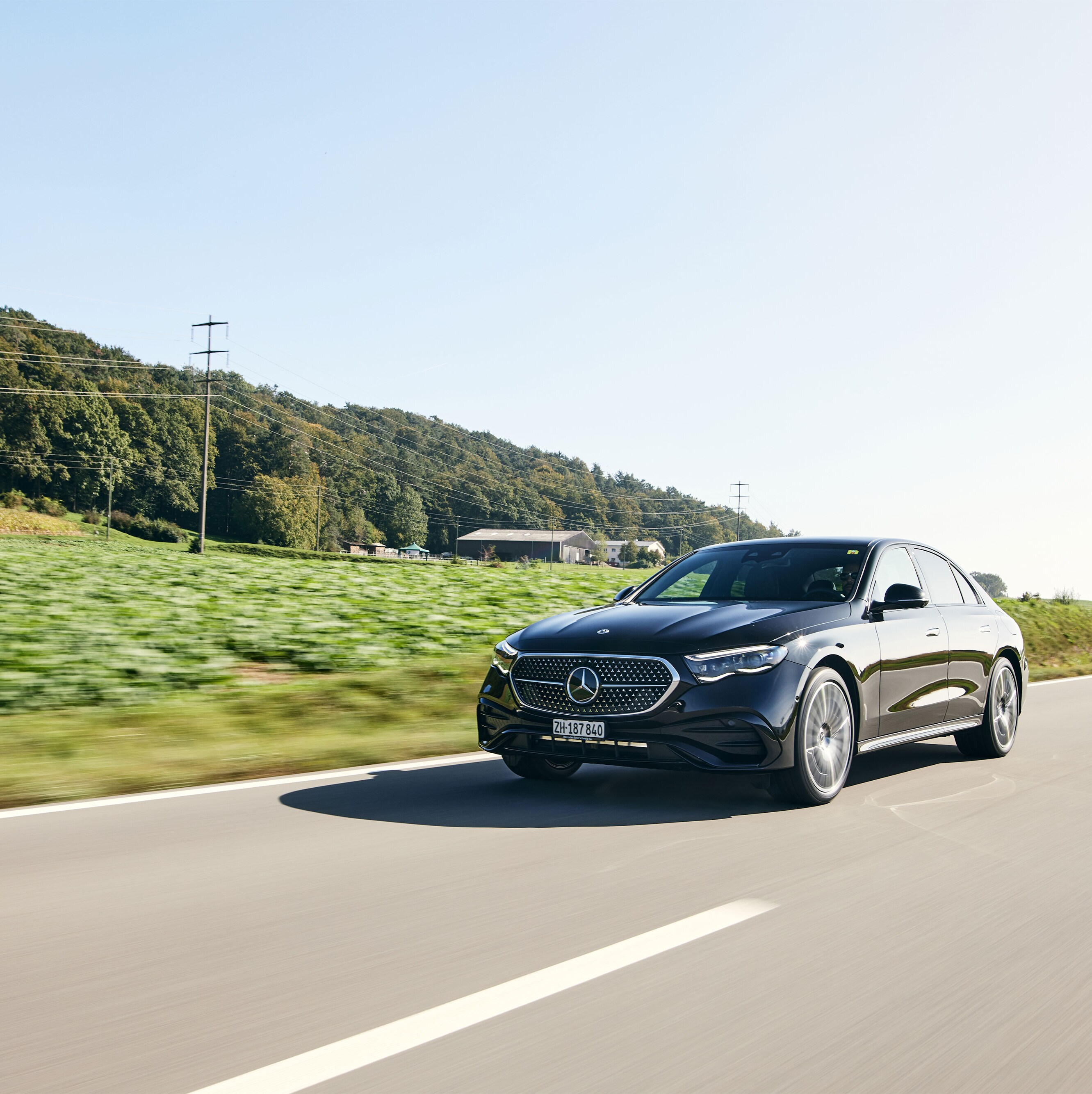 Une Mercedes-Benz Classe E noire dotée de la technologie hybride roule sur une route de campagne. 