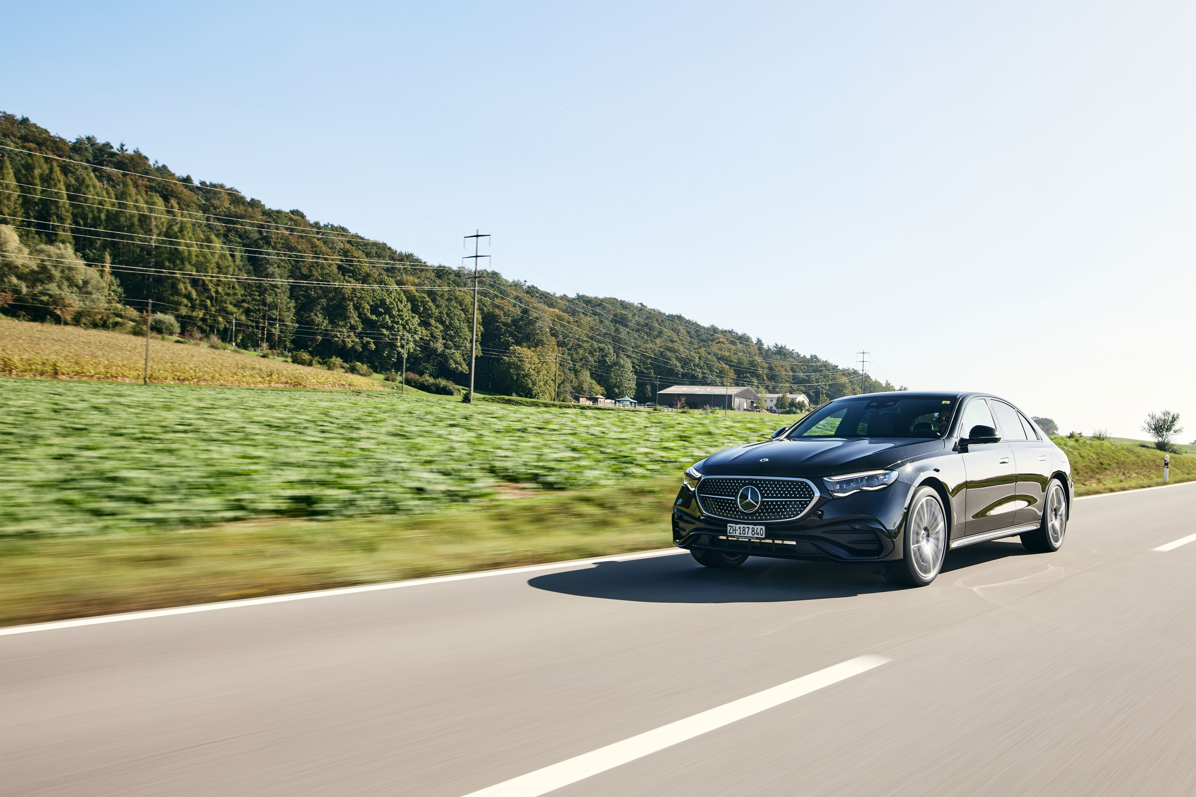 Une Mercedes-Benz Classe E noire dotée de la technologie hybride roule sur une route de campagne. Une Mercedes-Benz Classe E noire dotée de la technologie hybride roule sur une route de campagne.