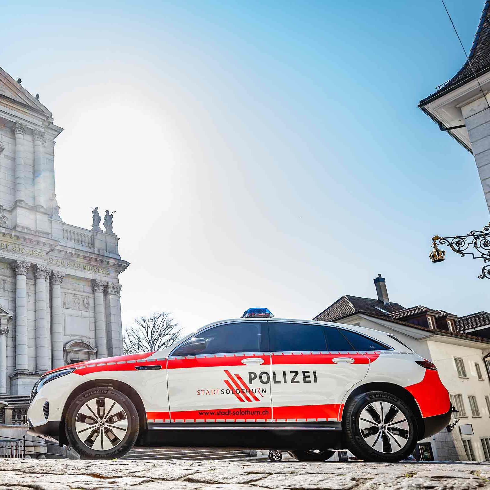 Vue latérale d’un Mercedes-Benz EQC de la police municipale dans la vieille ville de Soleure.
