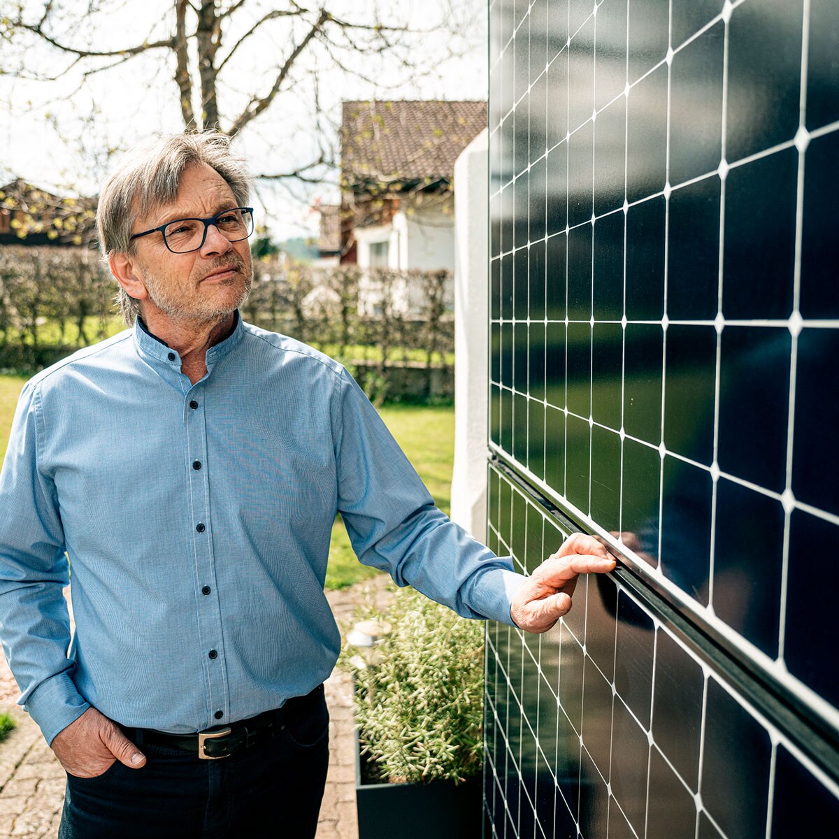 Mann betrachtet Solarpanels an der Hausfassade.