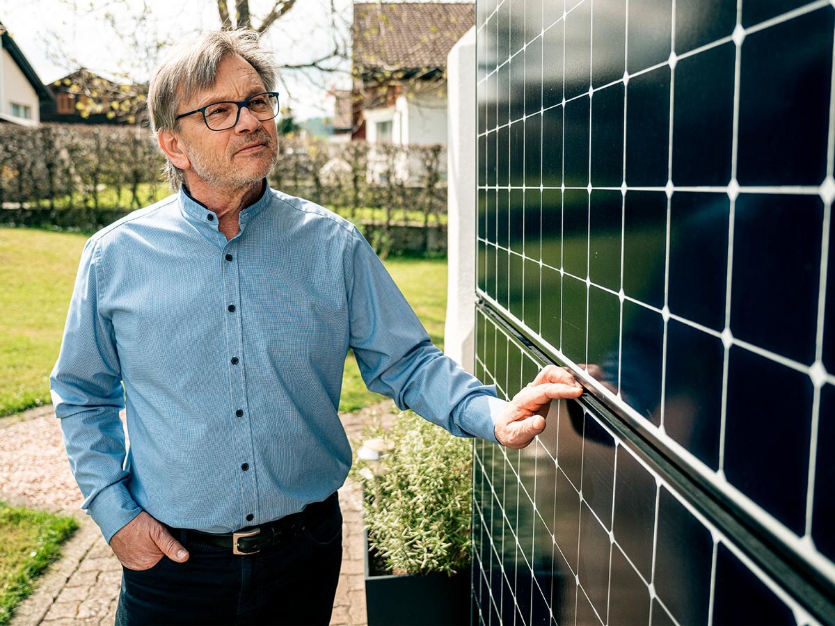 Un homme inspecte des panneaux solaires sur une façade de maison