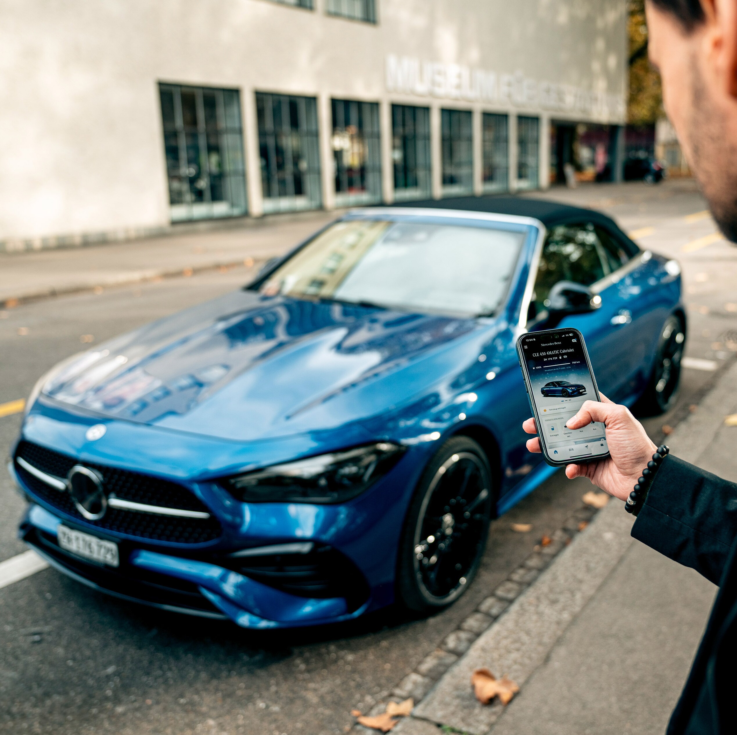 Ein blauer Mercedes-Benz CLE 450 4MATIC Cabriolet wird mittels App entriegelt.