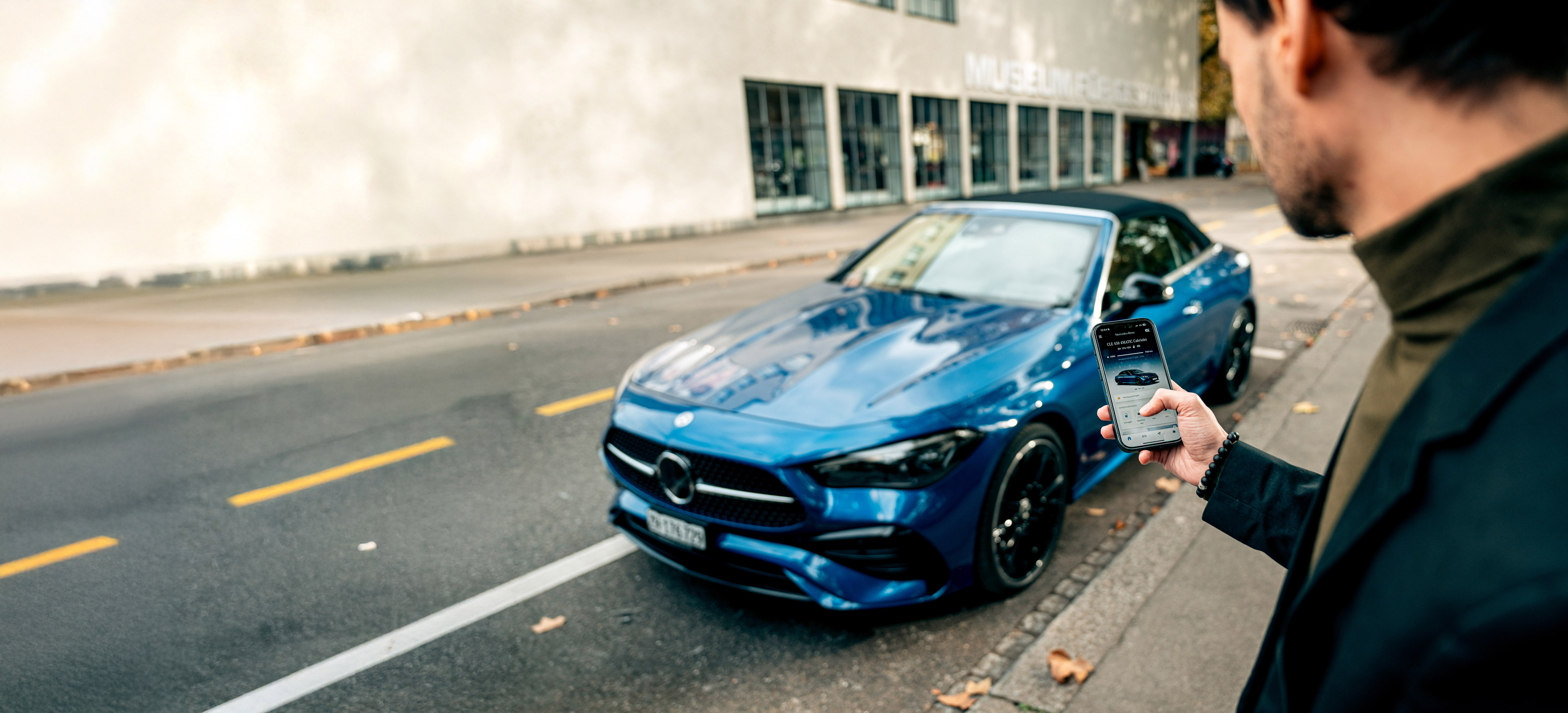 Ein blauer Mercedes-Benz CLE 450 4MATIC Cabriolet wird mittels App entriegelt. Ein blauer Mercedes-Benz CLE 450 4MATIC Cabriolet wird mittels App entriegelt.